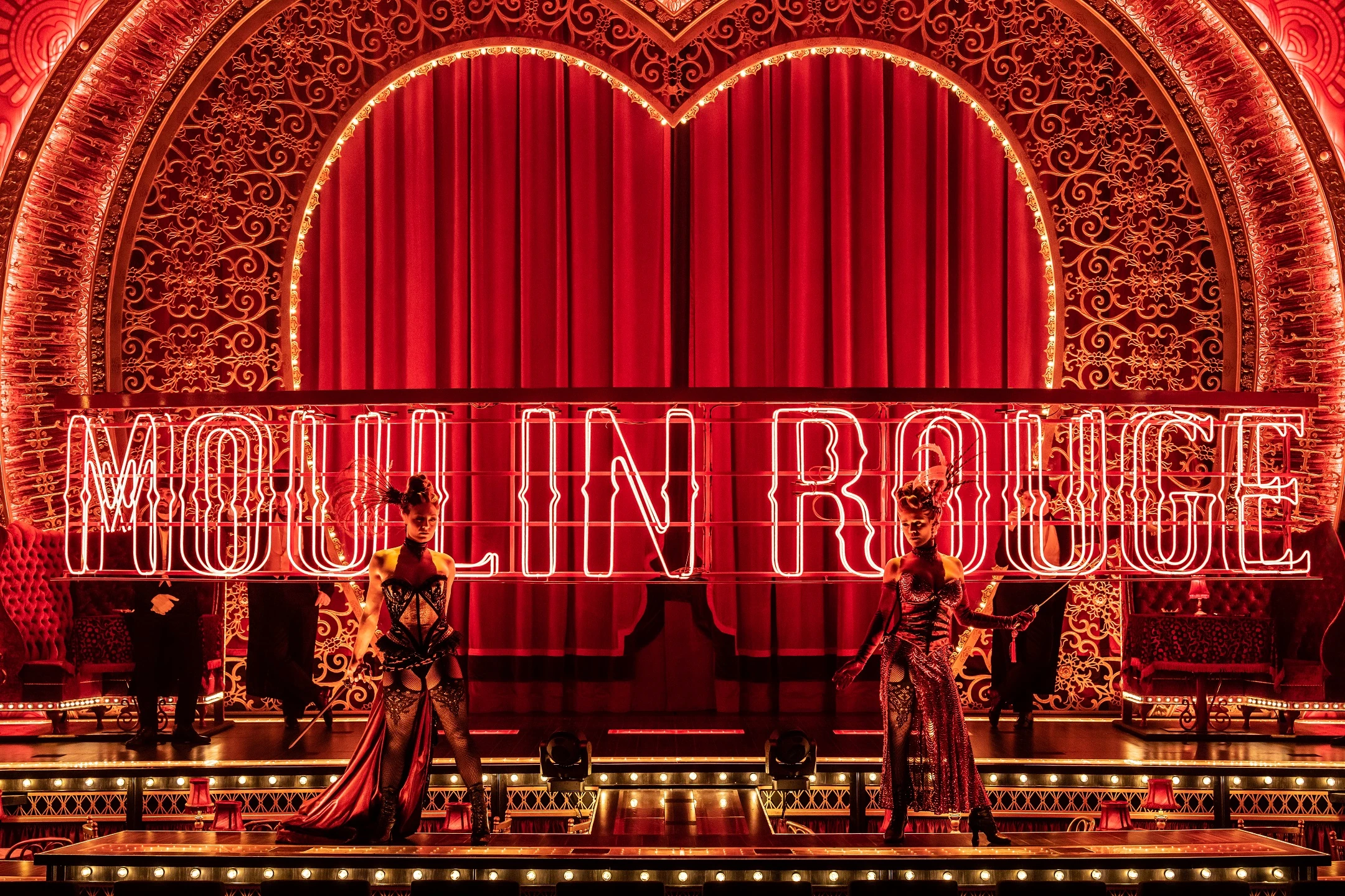 Aufführung im Moulin Rouge mit roten Lichtern und glamourösen Kostümen.