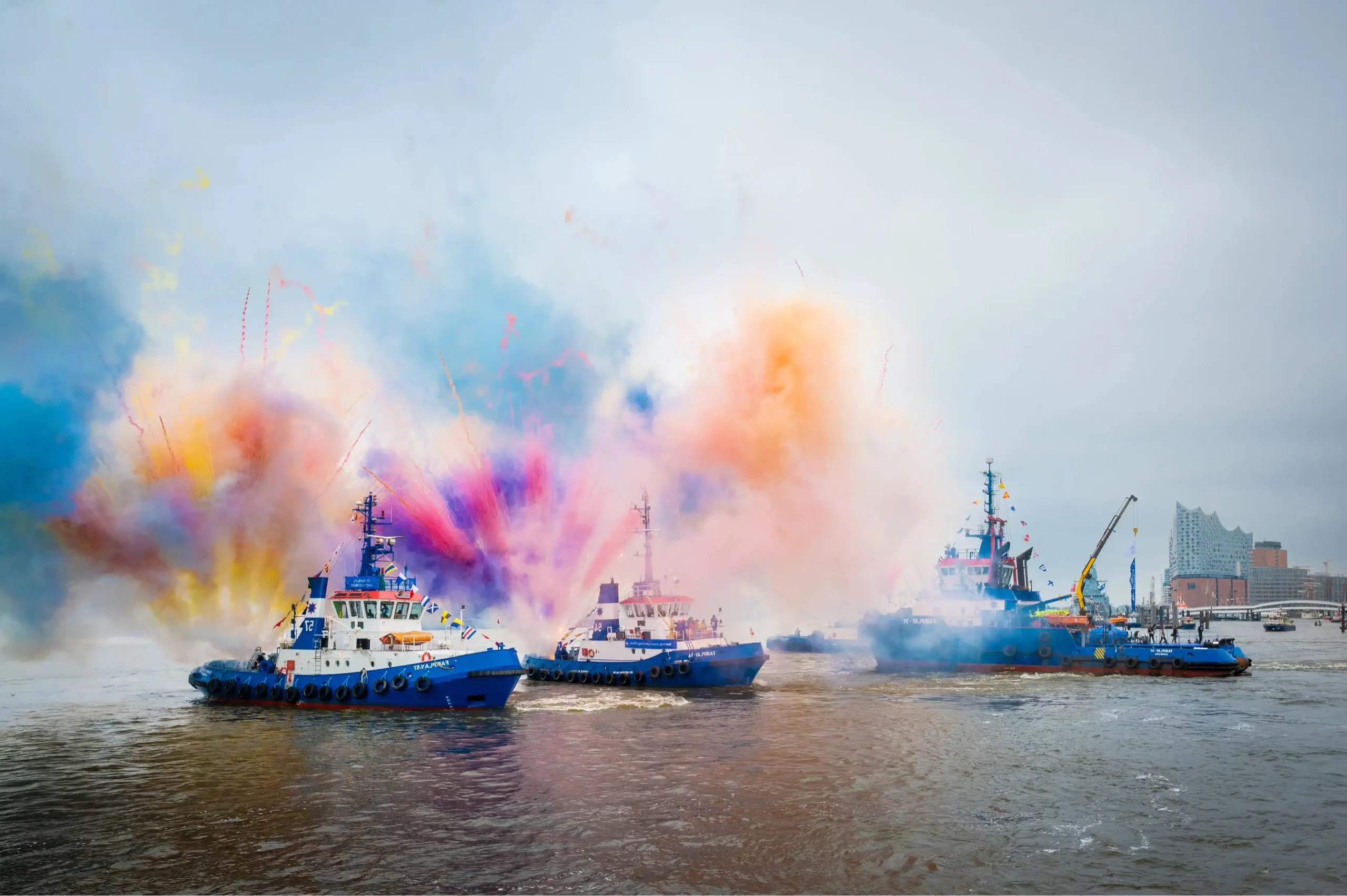 Schiffe im Hamburger Hafen schießen bunte Farben in die Luft.