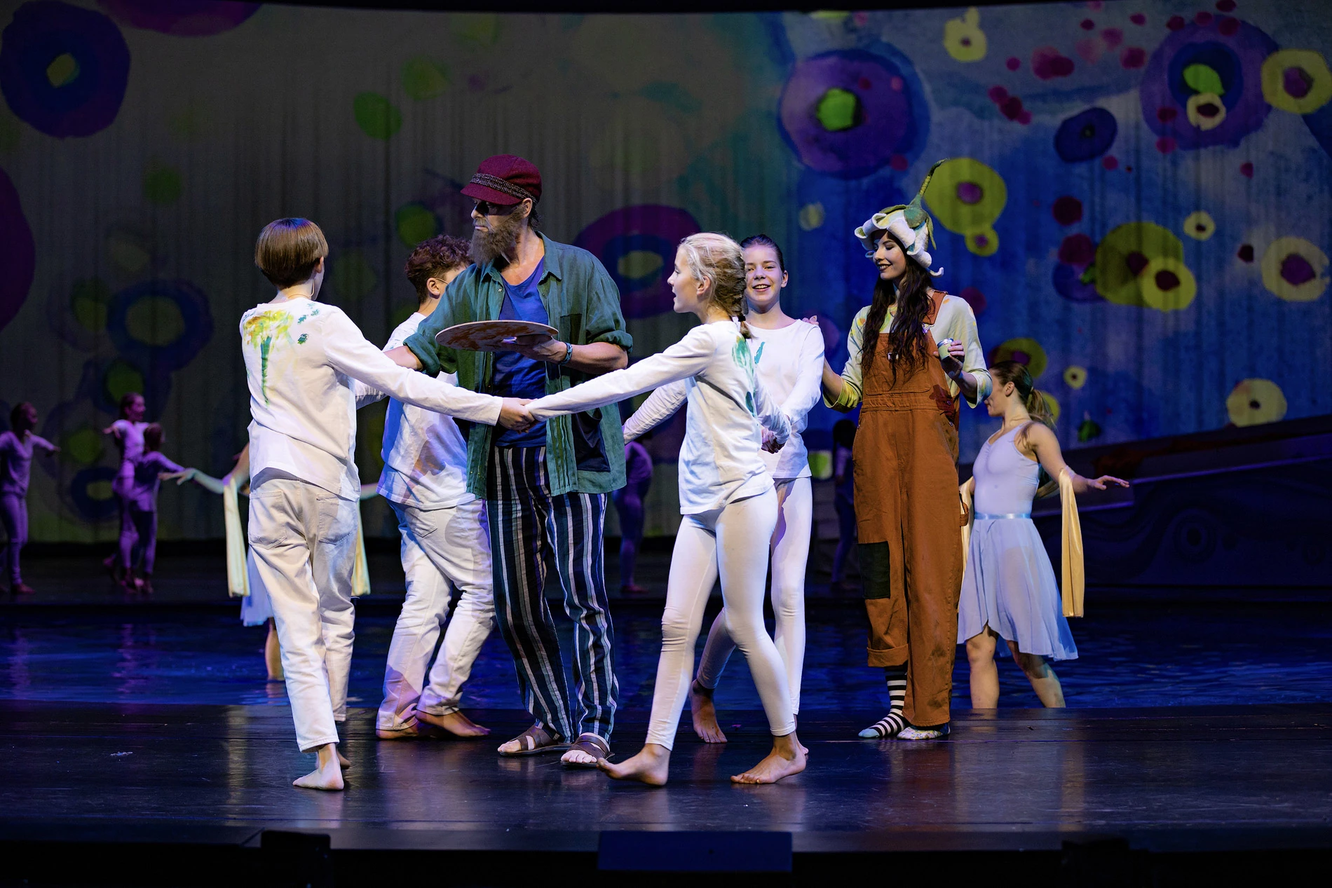 Eine kreative Theateraufführung mit Kindern in farbenfrohen Kostümen und einer künstlerischen Kulisse.