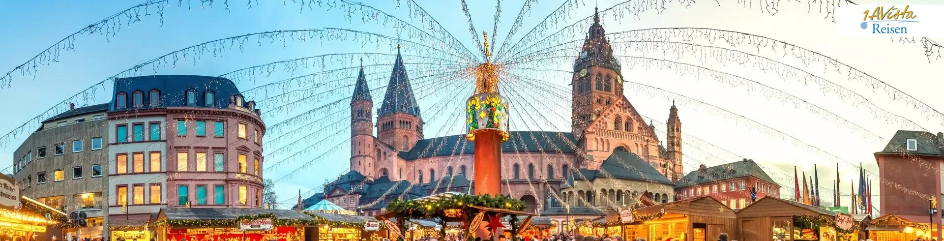 Weihnachtsmarkt mit beleuchteten Ständen und großer Lichterdekoration, im Hintergrund der Mainzer Dom bei Abenddämmerung