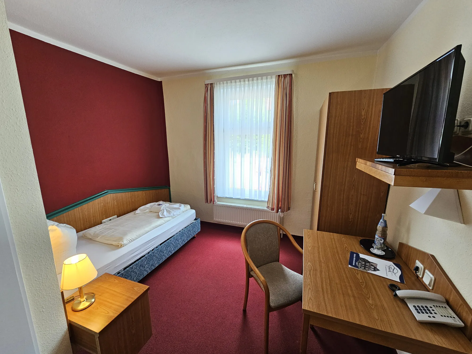 Ferienhotel Forelle Zimmerbeispiel - Einzimmerbett mit TV in farbiger Umgebung