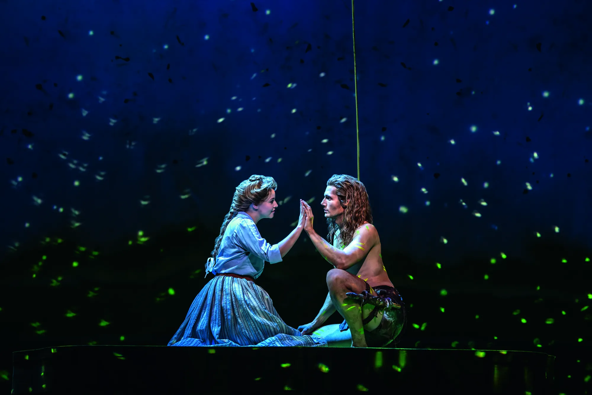 Tarzan Musical - lächelnde Frau und Tarzan knien sich nieder und berühren die Hand des anderen