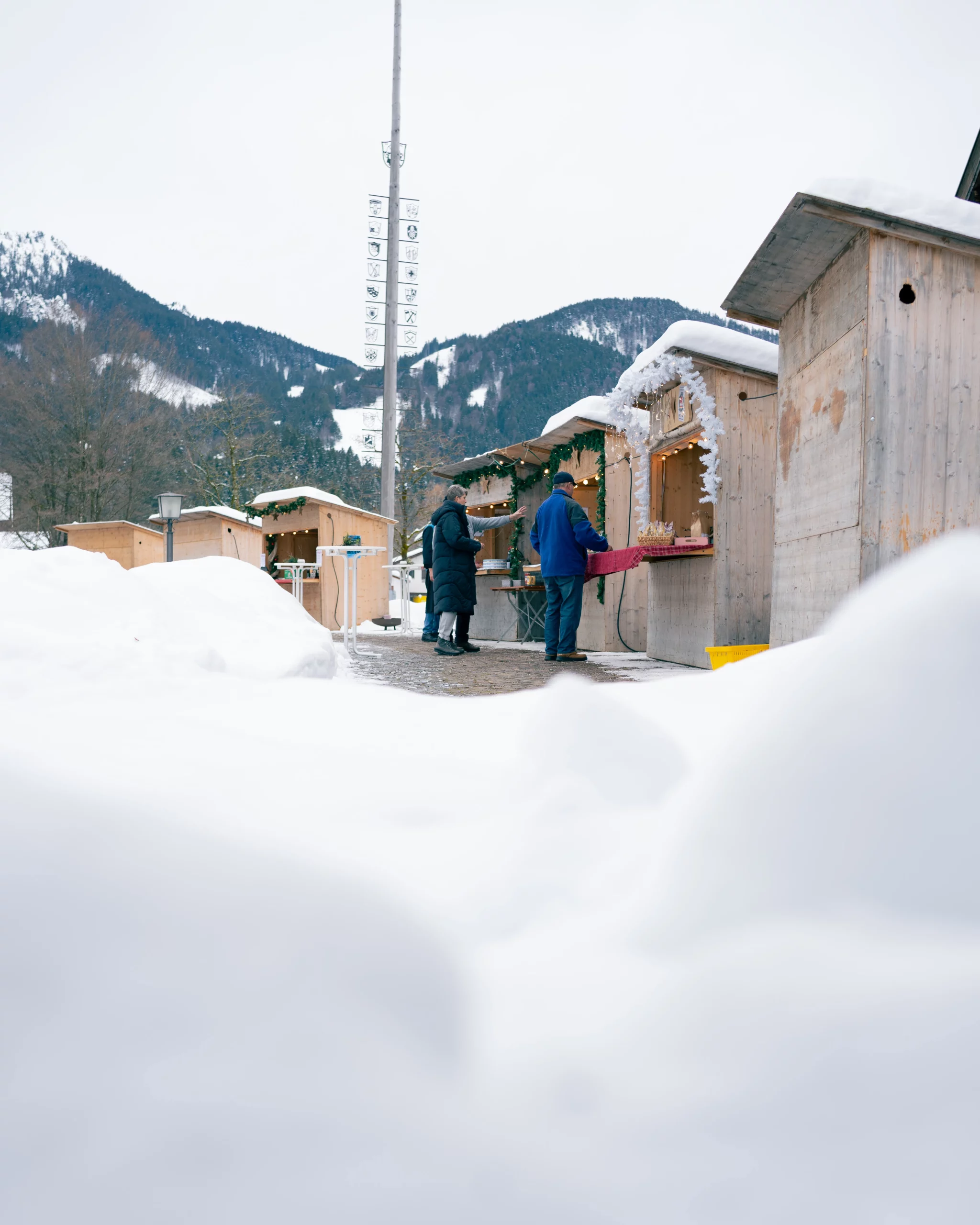 Diverse Marktstände mit Eröffnung beim Bratwürste auf einem Grill beim Ammergauer Winterzauber.