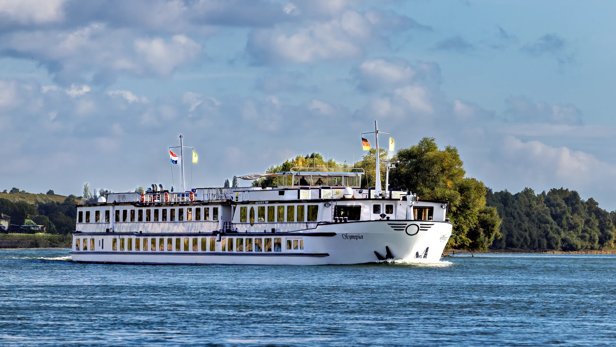 Außenansicht des Schiffs MS Olympia vor sonnigem Hintergrund auf einem Fluss bei Fahrt
