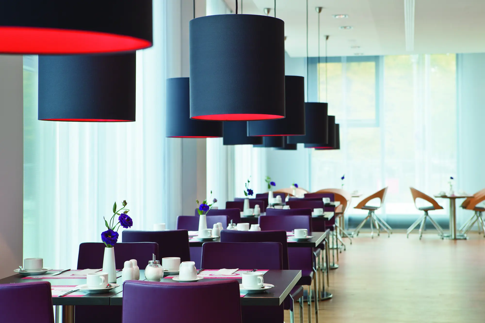 Restaurant im Intercity Hotel im Lila Syle gedeckte Tische mit blauen Blumen drauf