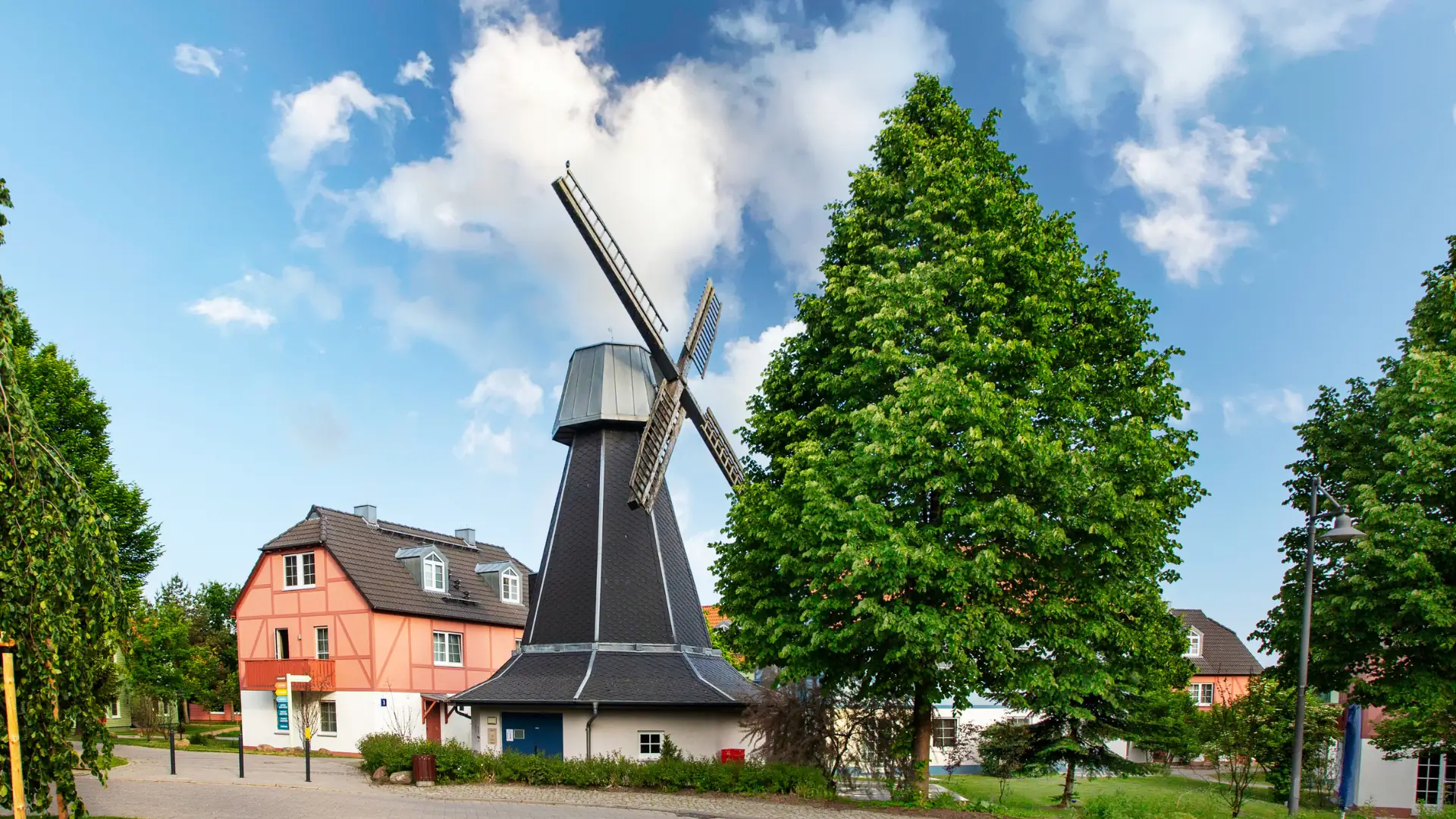 Historische Windmühle mit einem modernen Wohnhaus im Hintergrund.