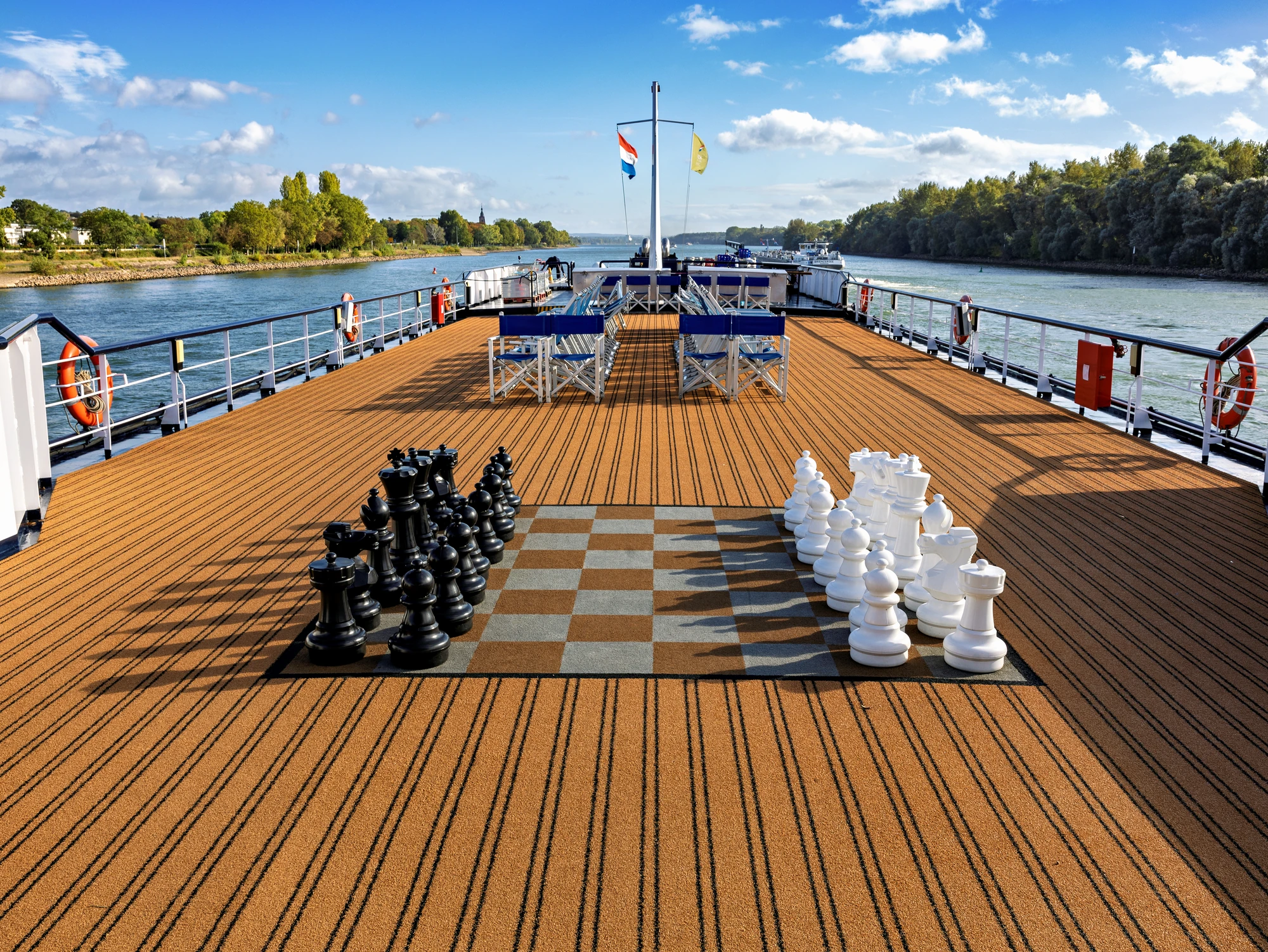 Sonnendeck der MS Olympia mit Schachfiguren und Stühlen vor sonnigem Hintergrund auf einem Fluss