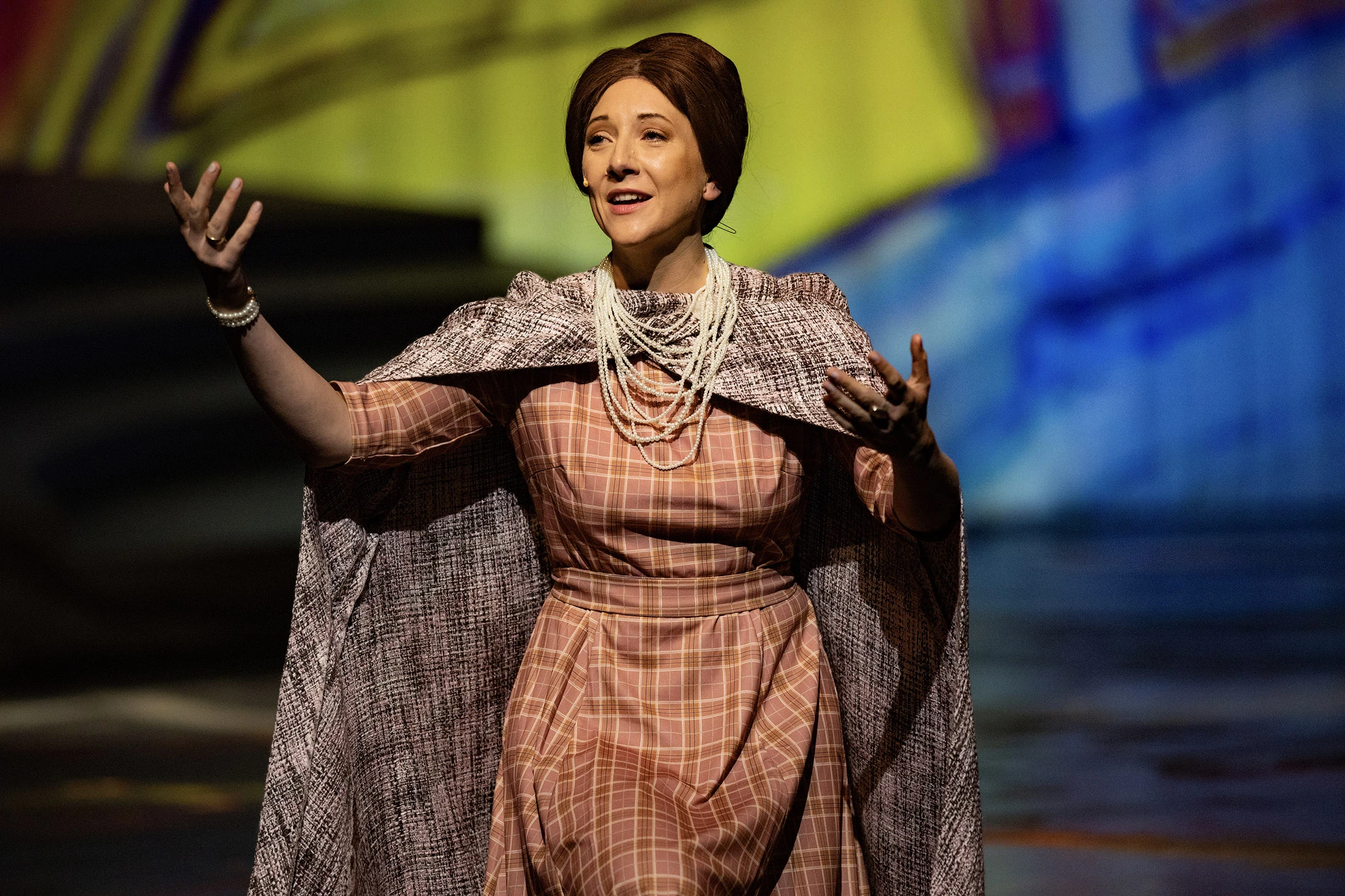 Dramatische Performance einer Frau mit einem Umhang und Perlenkette.