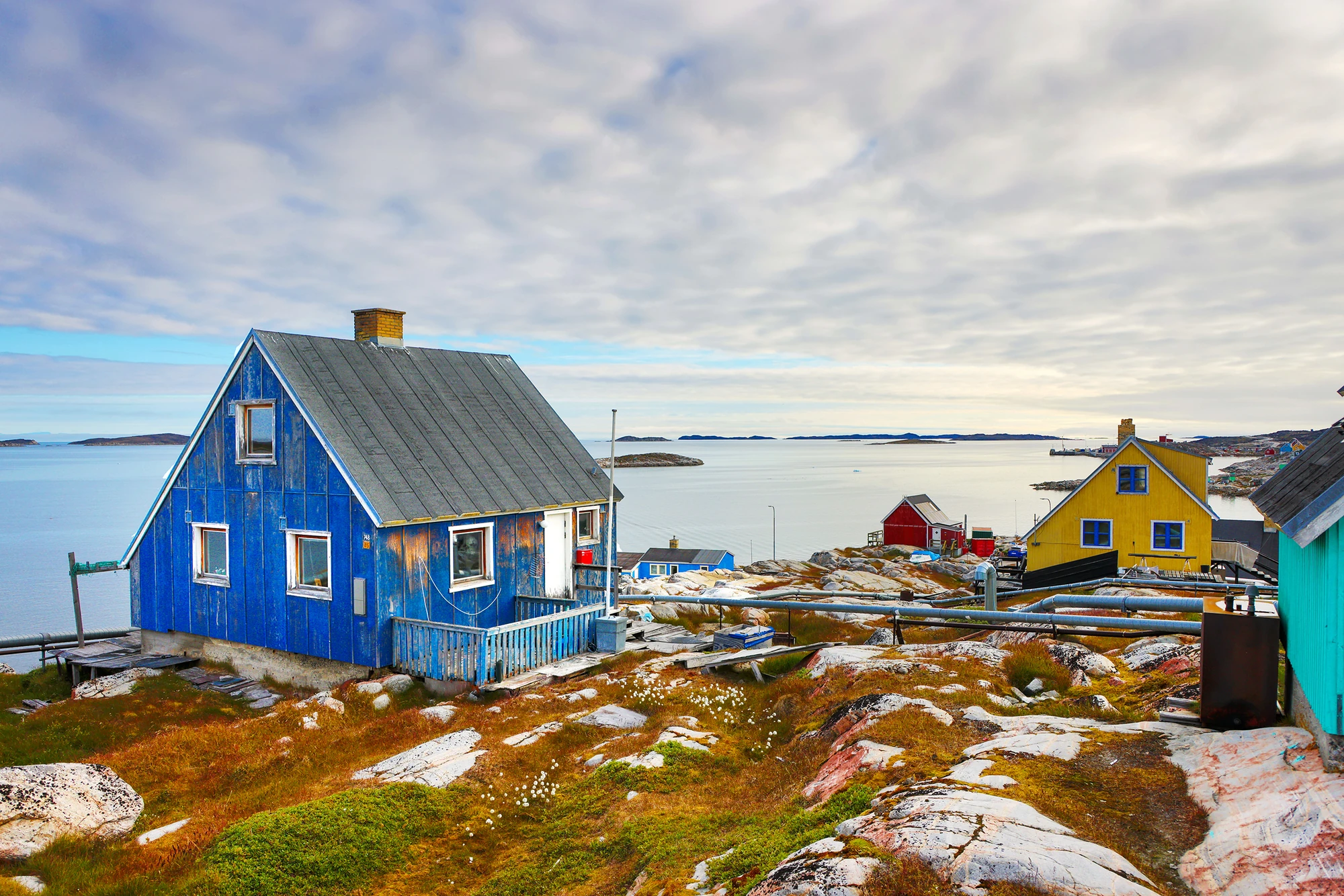 Eine blaue Hütte mit Blick auf das Wasser in Grönland.