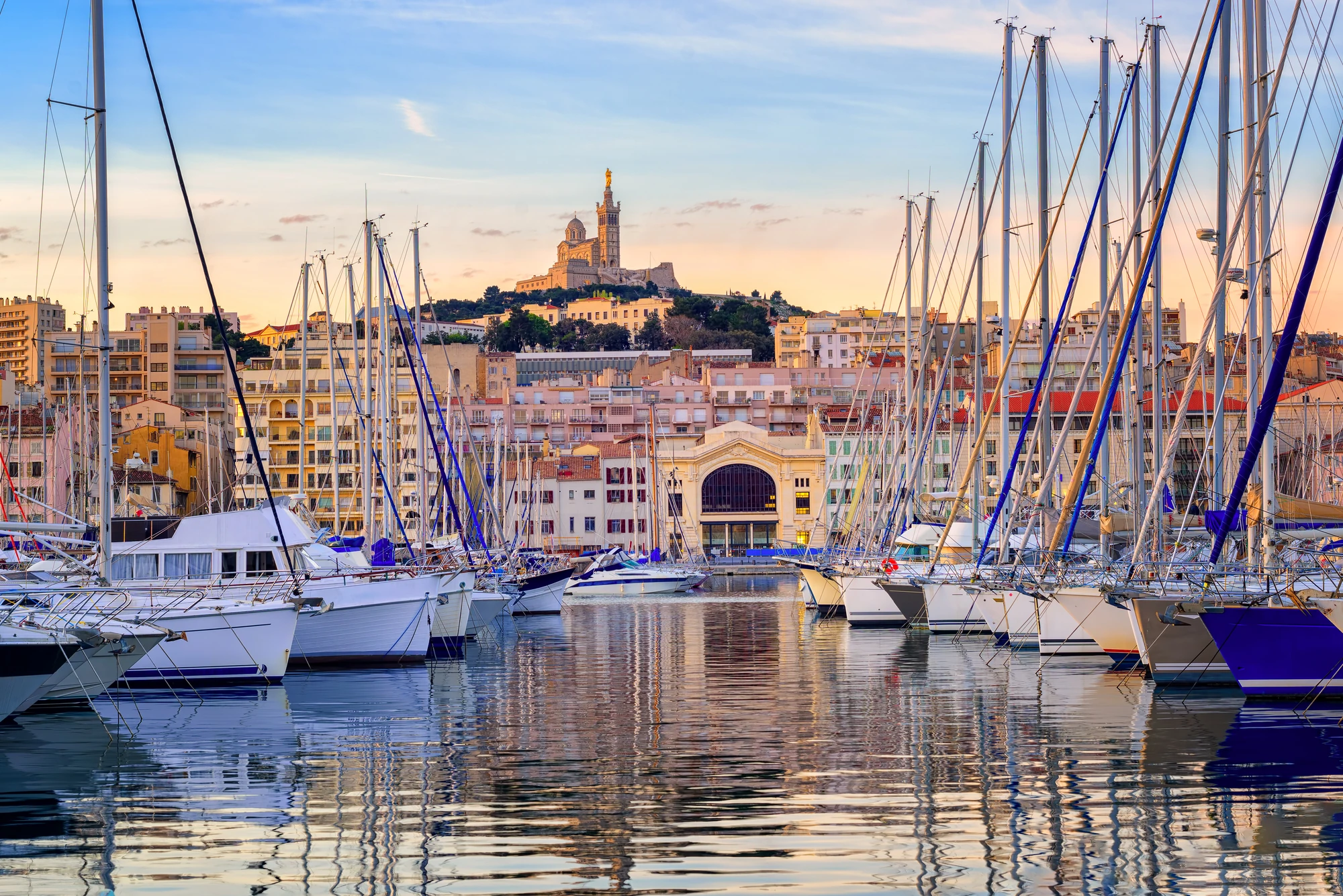 Blick auf den Hafen von Marseille mit Segelbooten im Vordergrund.