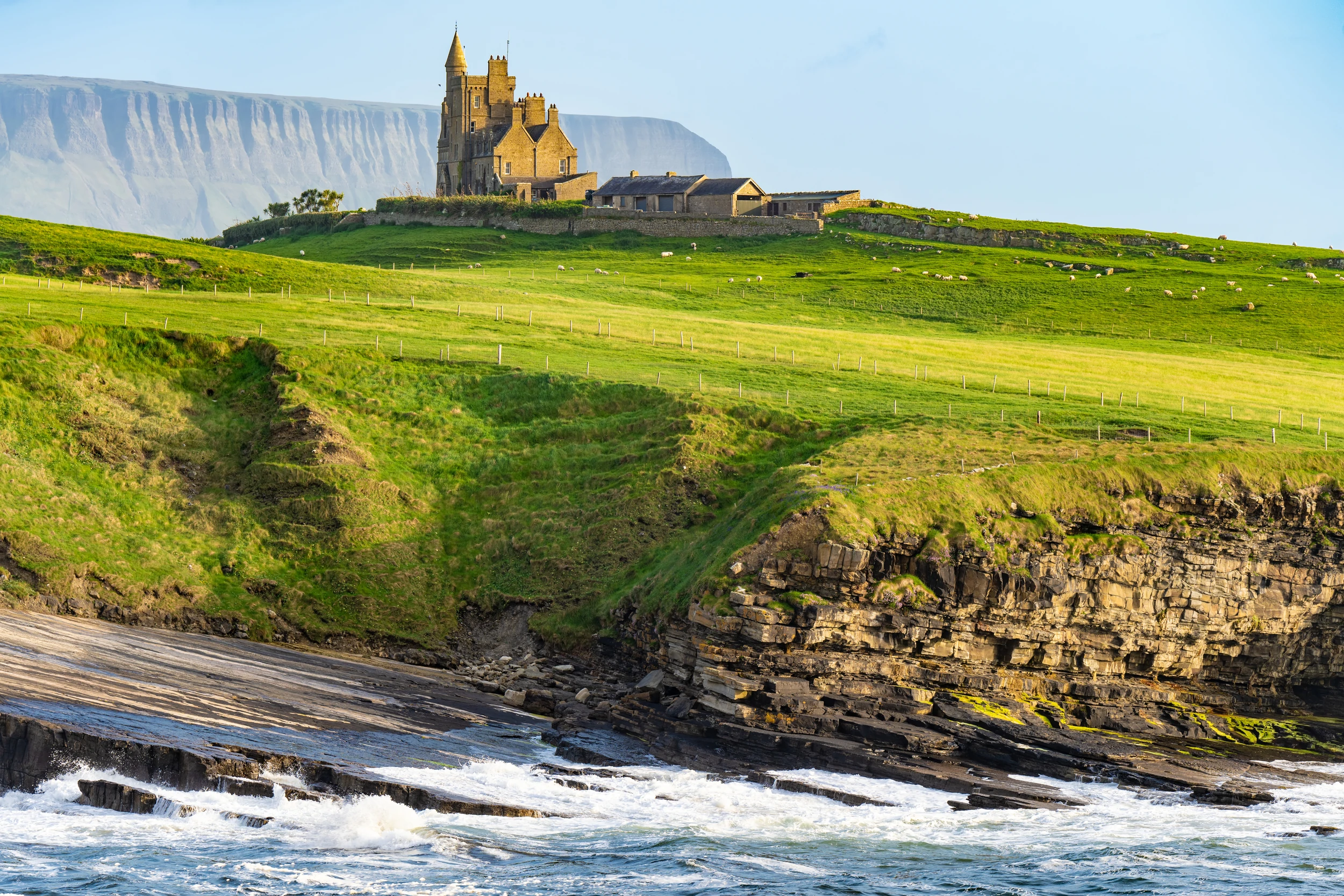 Berühmtes Classiebawn Castle in der malerischen Landschaft von Mullaghmore Head. Spektakulärer Sonnenuntergang mit Wellen, die an die Küste rollen. Wahrzeichen entlang des Wild Atlantic Way ... Mehr anzeigen