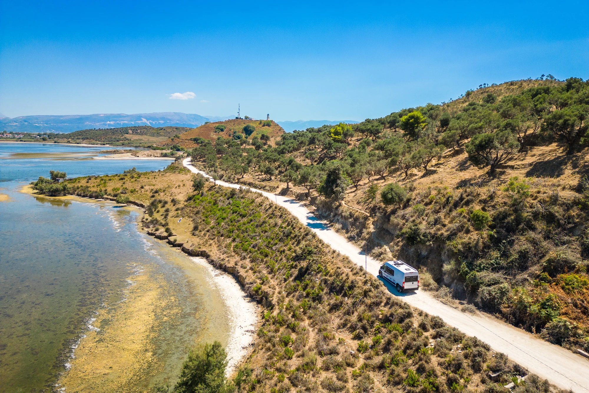 Albanien:Ein Wohnmobil, Campervan oder Reisemobil fährt auf einer Schotterstraße vom Strand Zvernec oder Dalan in der Nähe von Vlora,