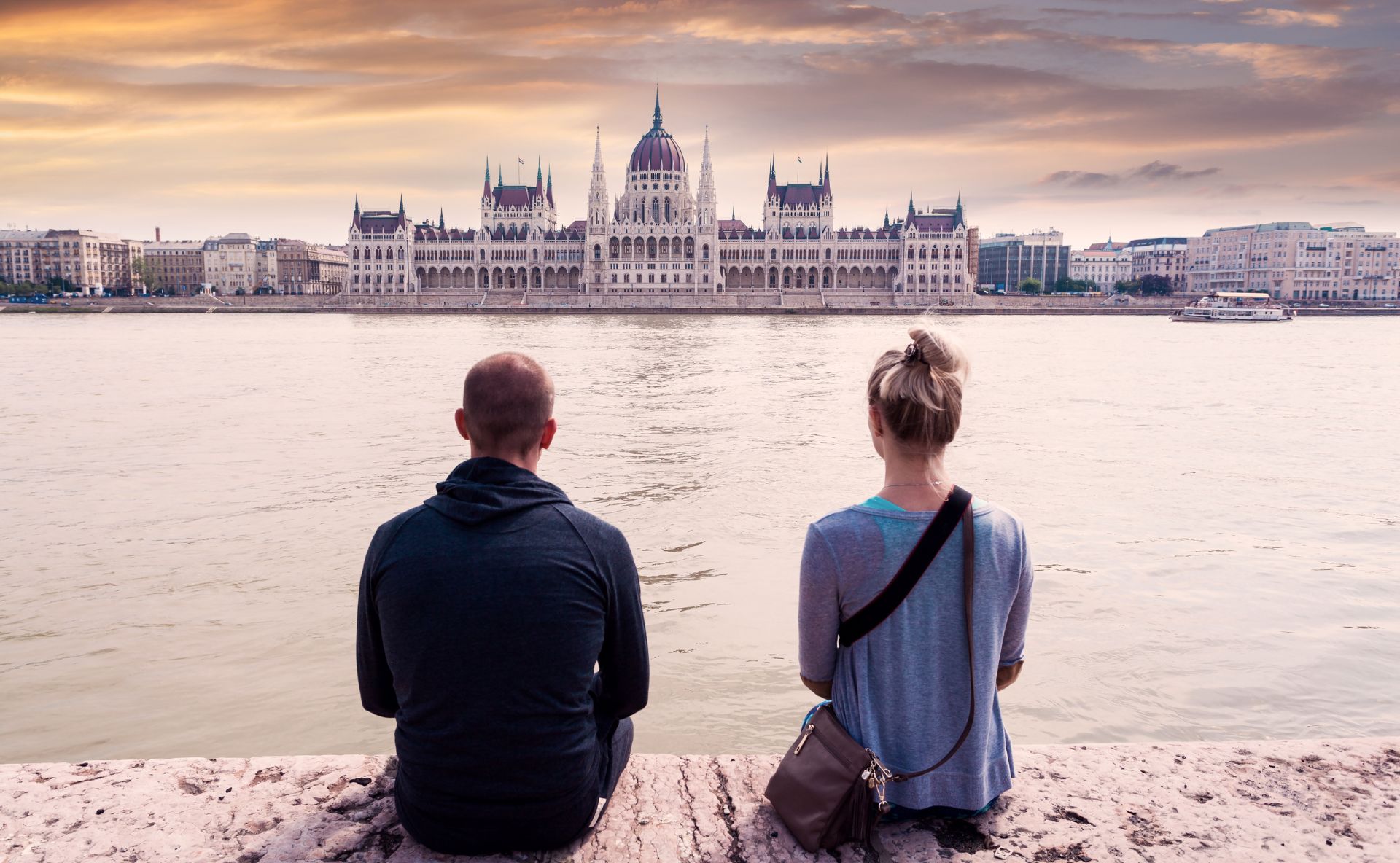 Pärchen sitzt am Donauufer mit Blick auf Budapest