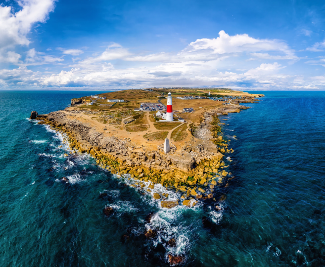 Portland Blick von einer historischen Festungsmauer auf eine Stadt mit weißen Gebäuden und dahinter das blaue Meer unter klarem Himmel.