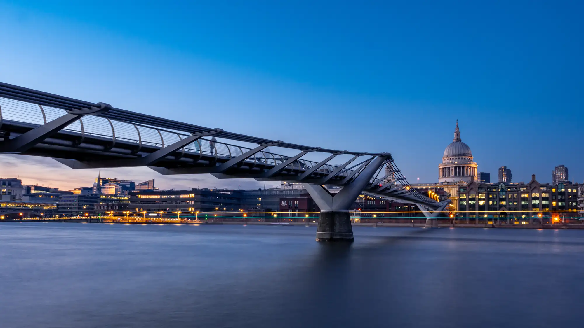 Die Millennium Bridge in London ist eine beeindruckende Fußgängerbrücke, die die Themse überspannt und die St. Paul's Cathedral mit dem Tate Modern und der Shakespeare's Globe Theatre verbindet. Sie wurde 2000 eröffnet und zeichnet sich durch ihr modernes Design aus, das aus einem schlanken Stahlrahmen und einer einzigartigen Schwingkonstruktion besteht. Bei Nacht wird die Brücke oft durch stimmungsvolle Beleuchtung in Szene gesetzt, was sie zu einem beliebten Fotomotiv macht. Die Millennium Bridge ist nicht nur ein wichtiges architektonisches Wahrzeichen, sondern auch ein beliebter Ort für Spaziergänge und Ausblicke auf die Stadt.
