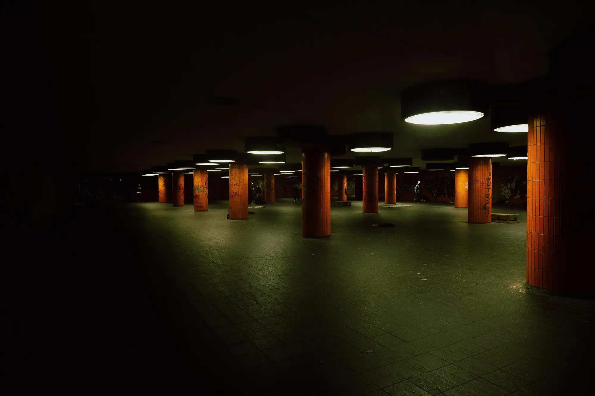 Orangefarbene Pfeiler mit Lichtern und grünem Boden in der Messedamm Unterführung Berlin