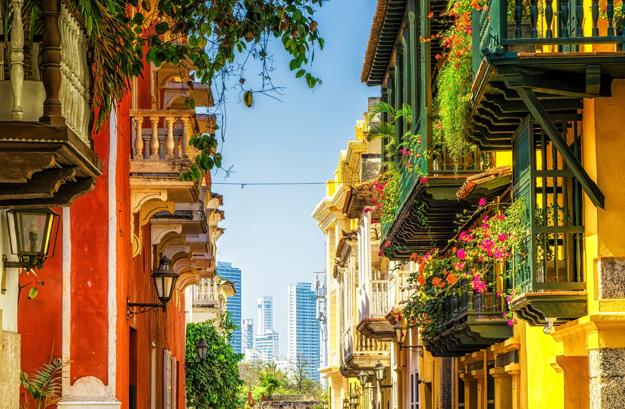 Bunte Balkone in Cartagena mit Blumen und modernen Gebäuden im Hintergrund.