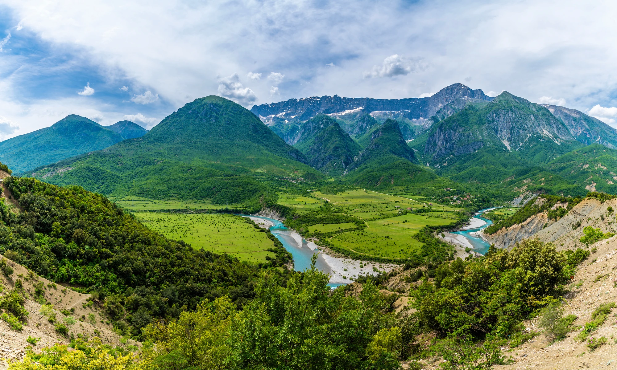 Albanien: Ein Weitwinkelblick über das Vjosa-Flusstal und die Nemercka-Gebirgskette in Albanien im Sommer.