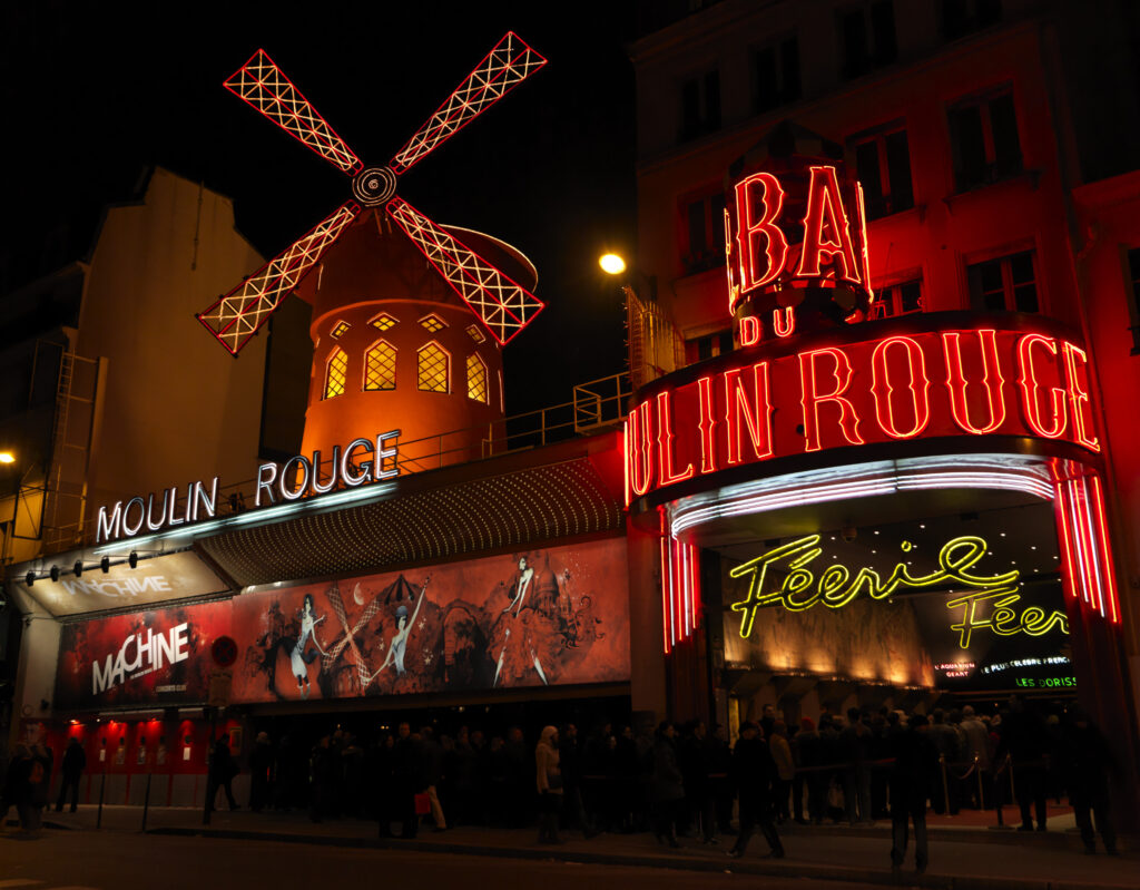 Moulin Rouge Paris Außenansicht bei Nacht mit rotem Schriftzug und Mühle