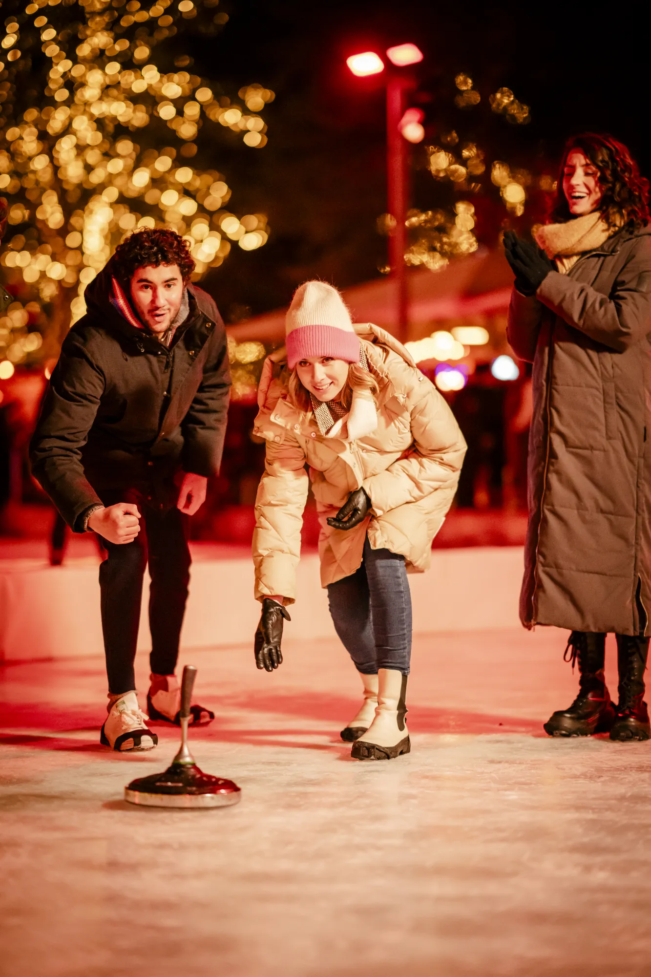 Autostadt Wolfsburg - junge Erwachsene spielen auf der Eislaufbahn Eisstockschießen im dunklen Rotlicht