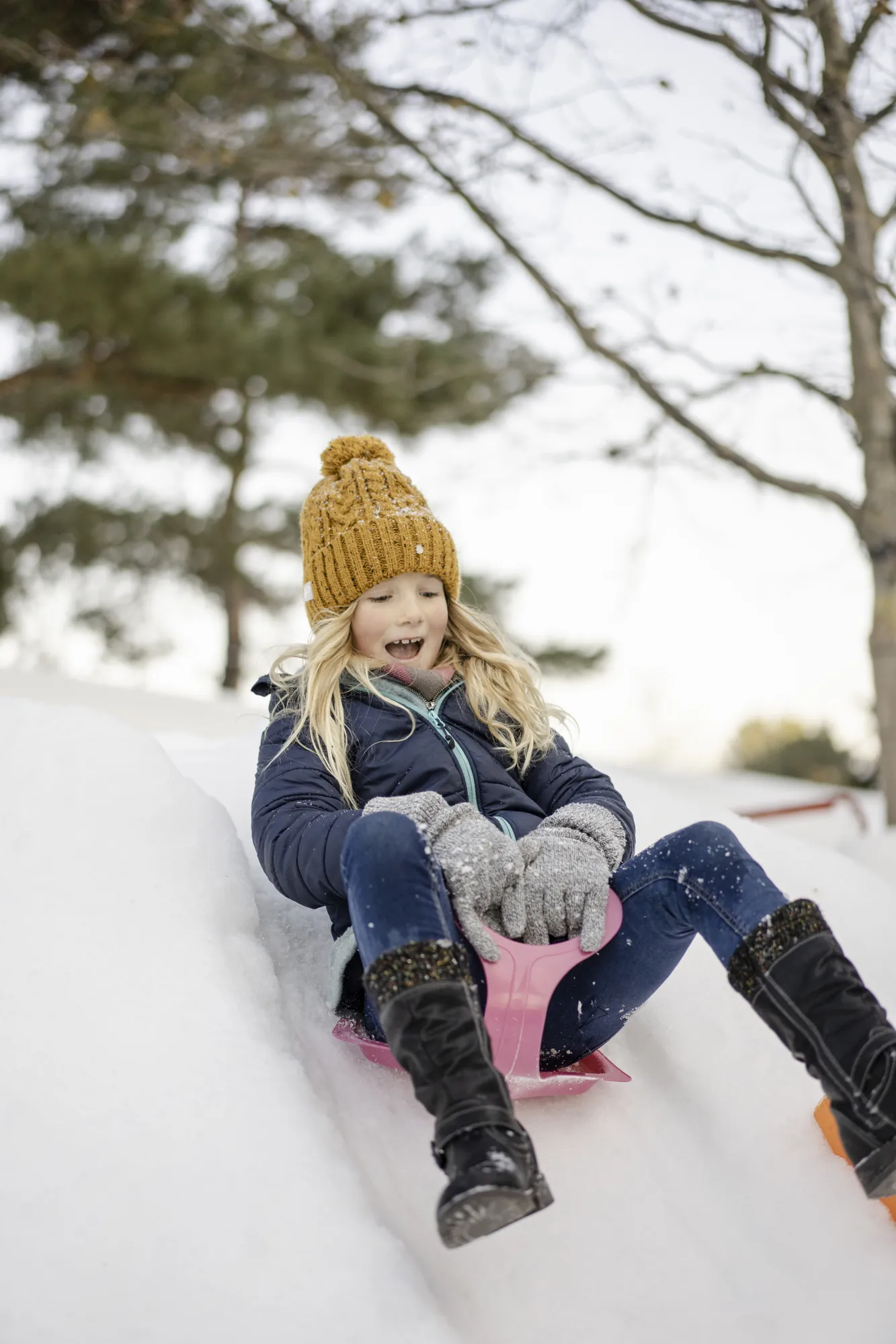 Autostadt Wolfsburg - junges Mädchen rutscht auf einem Schlitten einen Eishügel hinunter