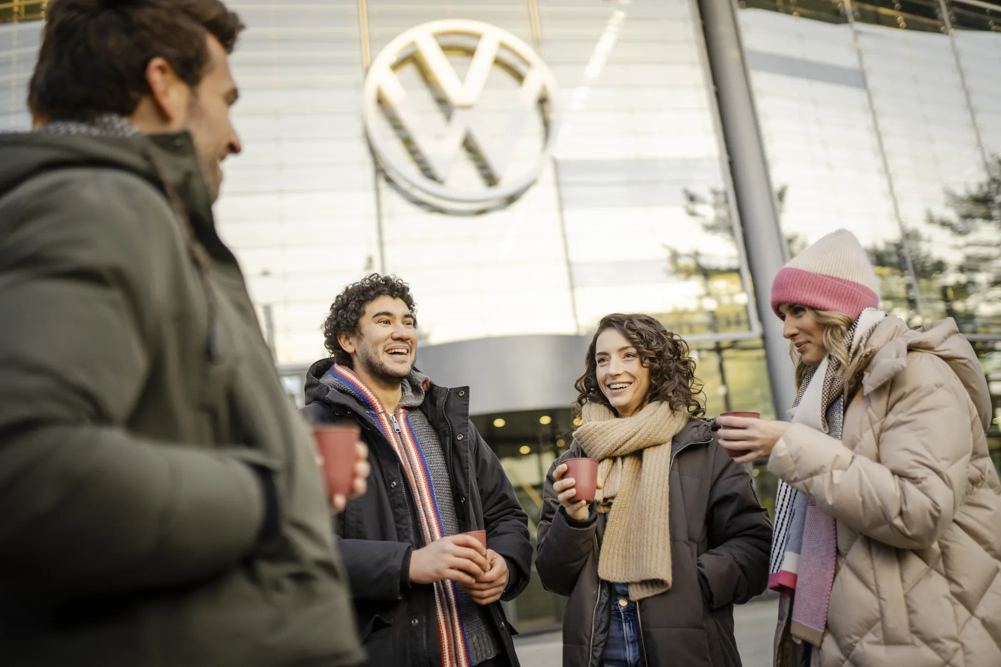 Autostadt Wolfsburg - junge Erwachsene vor dem VW-Gebäude mit einem Getränk in der Hand