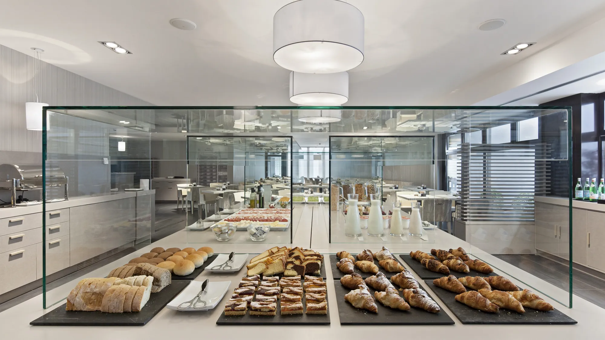 NH Parma - Aussicht auf das Frühstücksbuffet mit Brötchen, Gebäck, Kuchen, Müsli im eleganten Frühstücksbereich