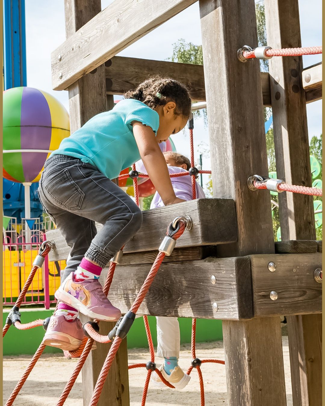 Kleines Mädchen klettert auf dem Heide Park Spielplatz