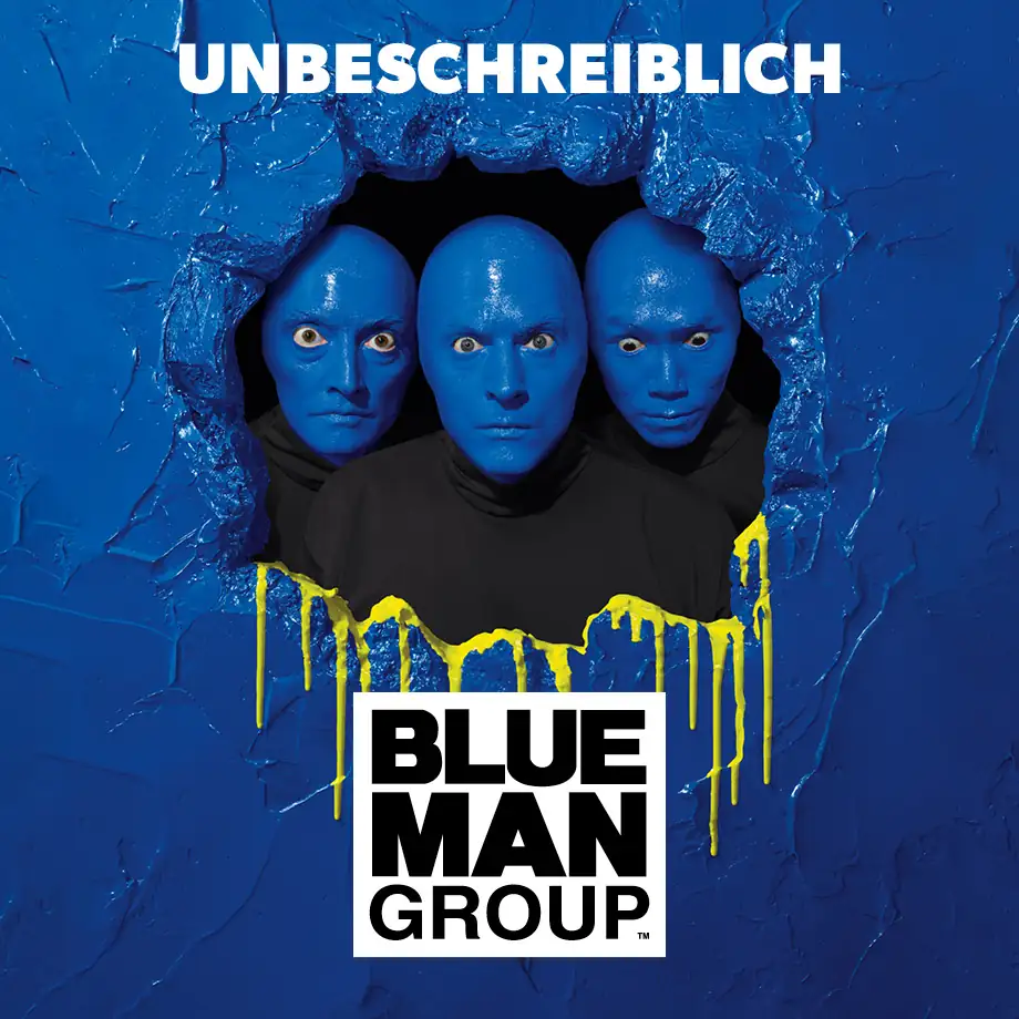 Drei blau bemalte Männerköpfe mit schwarzen Hemden schauen durch ein Loch in einer blauen Wand, darüber steht 'UNBESCHREIBLICH', darunter das Logo 'BLUE MAN GROUP'