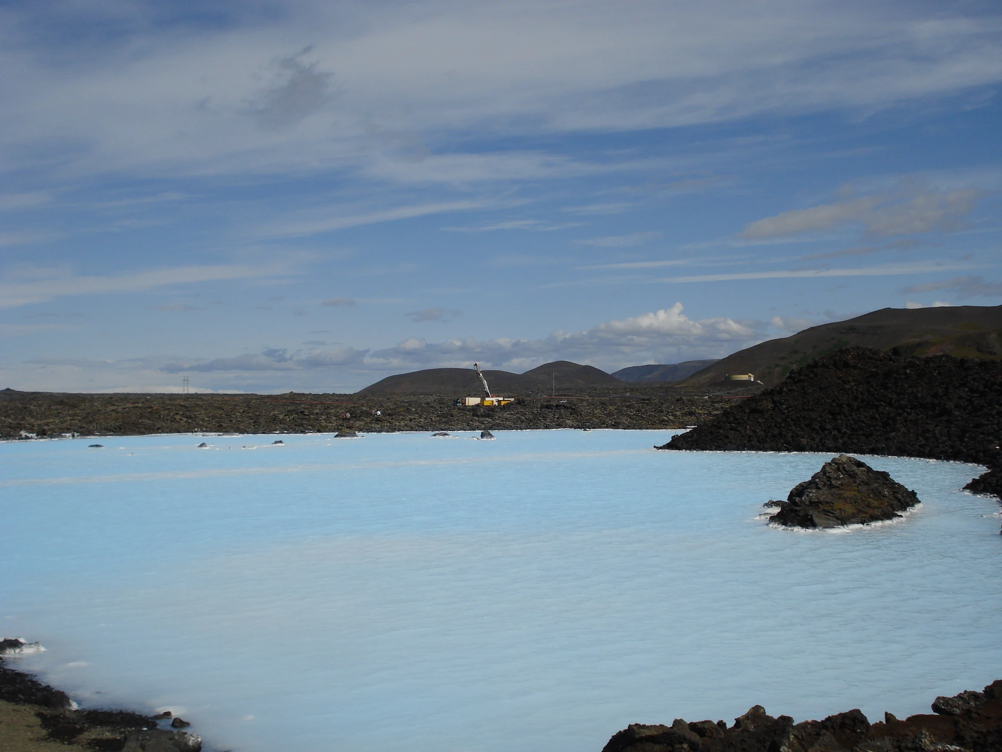 Blaue Lagune Island Helles, milchig-blaues Wasser einer Lagune, umgeben von dunklen, vulkanischen Felsen unter bewölktem Himmel.