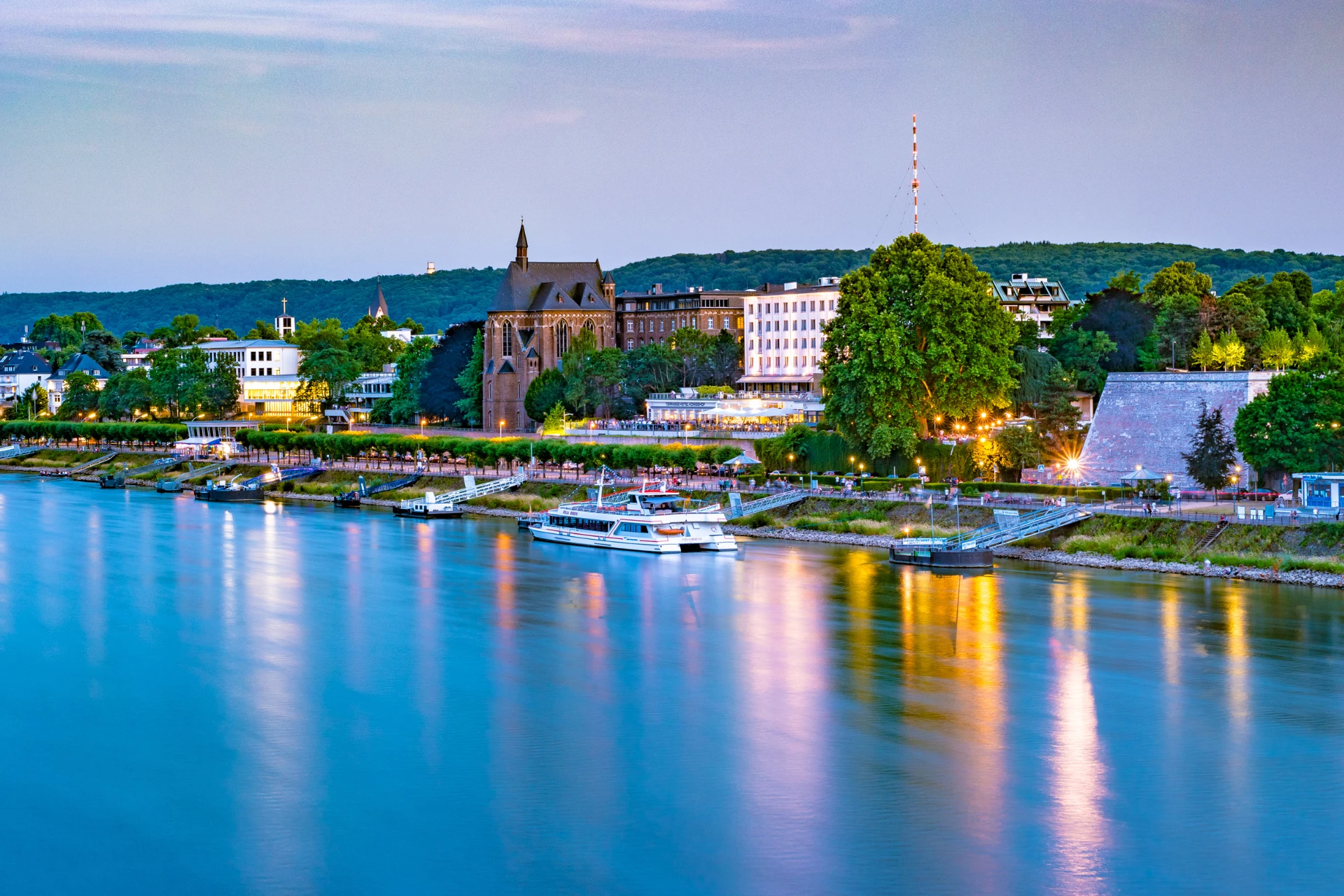 Weihnachtsmarkt bei Nacht mit beleuchtetem Weihnachtsbaum, großer Weihnachtspyramide und Marktständen, Menschen im Vordergrund