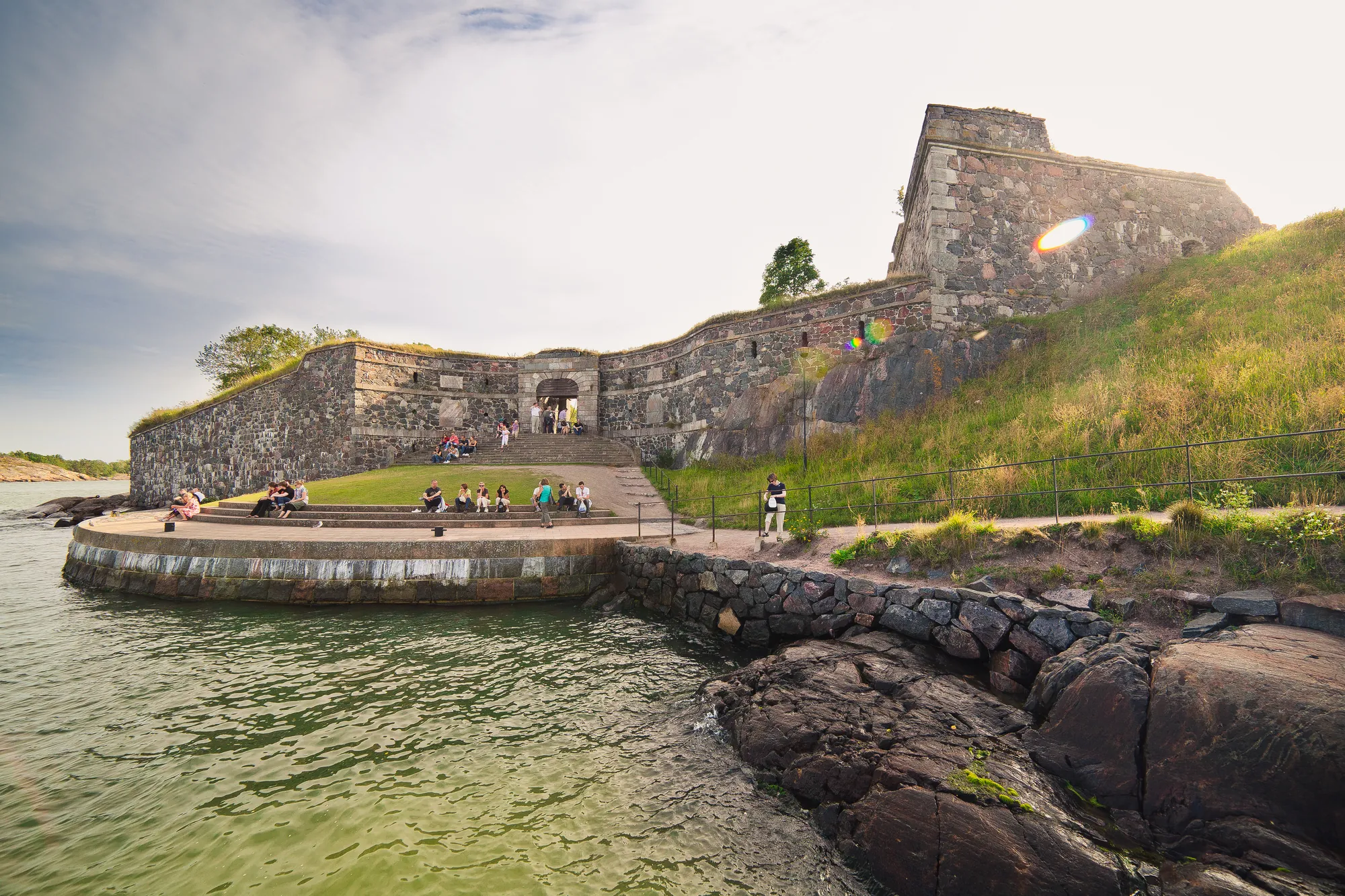 Aussicht auf die Insel Suomenlinna in Helsinki, mit ihren historischen Mauern und Menschen, die die malerische Landschaft und die beeindruckende Festungsarchitektur genießen.