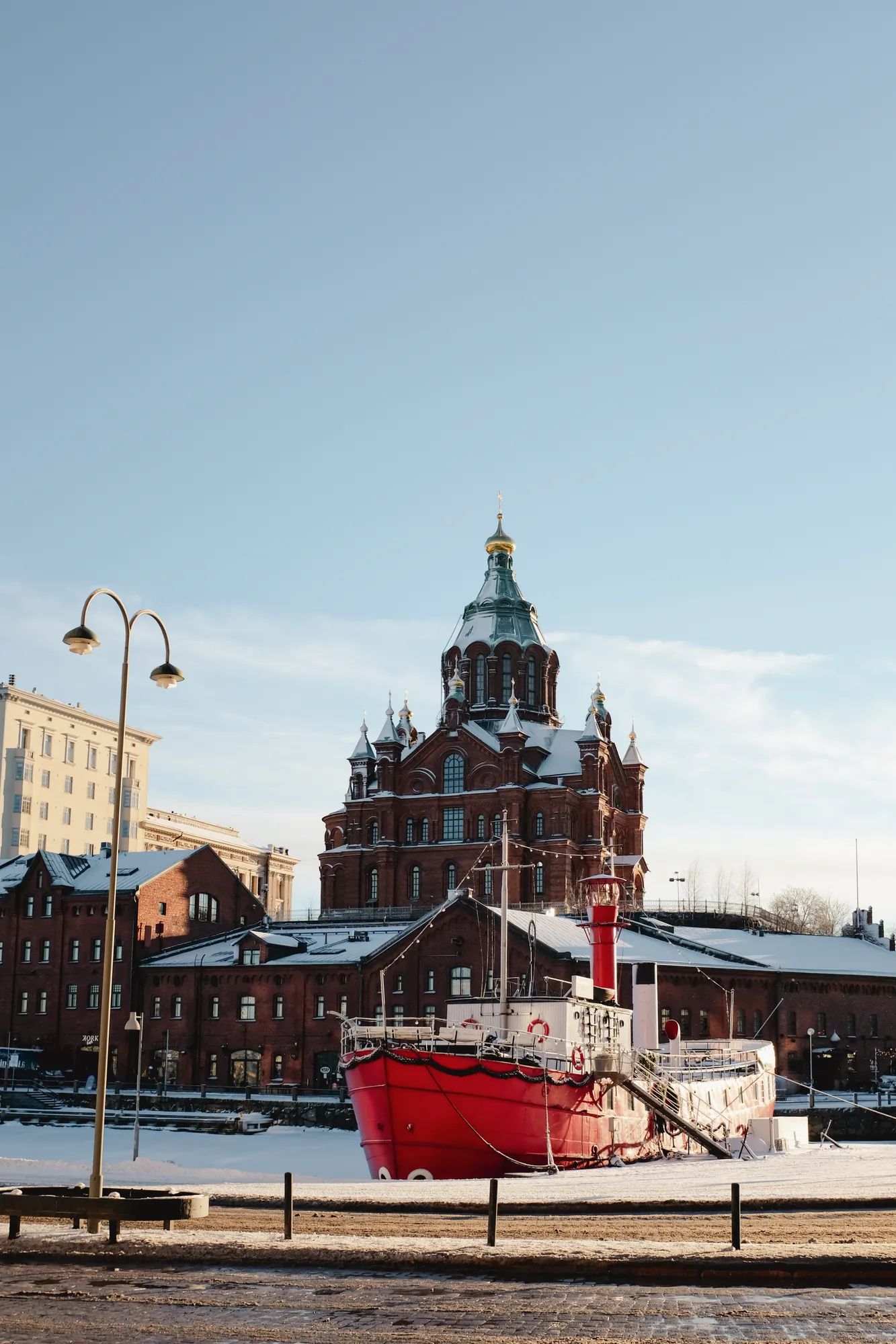 Uspenski Kathedrale liegt auf der Halbinsel Katajanokka im Zentrum, leicht mit Schnee bedeckt, während ein Schiff am Ufer davor liegt und die malerische winterliche Szene ergänzt.