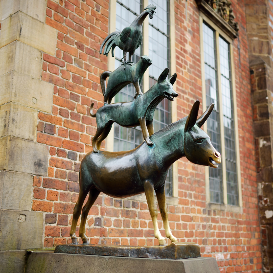 Dieses Foto zeigt die berühmte Bronzestatue der Bremer Stadtmusikanten vor dem Rathaus in Bremen. Die Skulptur, inspiriert vom Märchen der Gebrüder Grimm, stellt einen Esel, einen Hund, eine Katze und einen Hahn dar, die symbolisch aufeinander stehen und ein Wahrzeichen der Stadt sind.