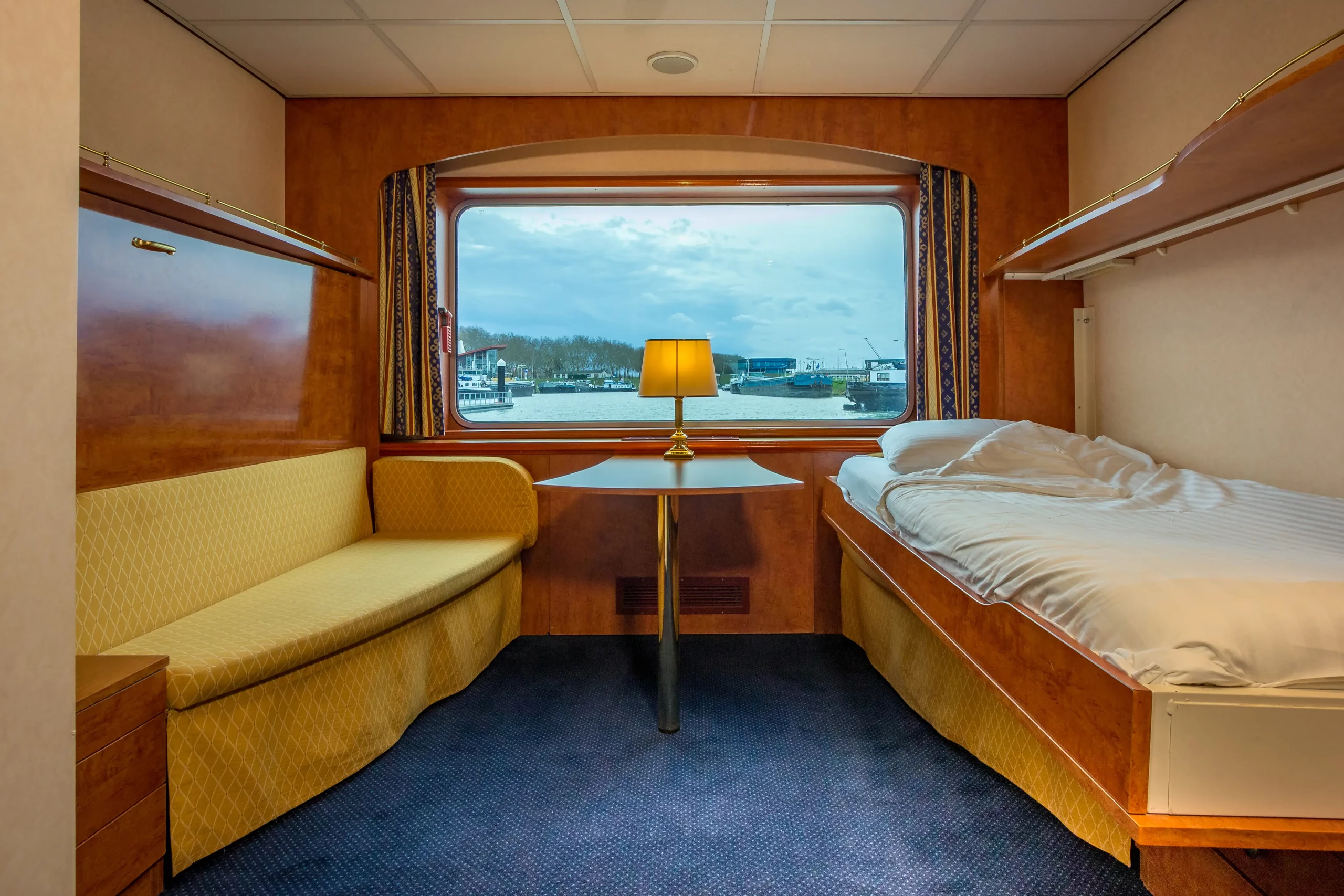 Wohnbereich in einer Schiffskabine mit Fenster und Lampe