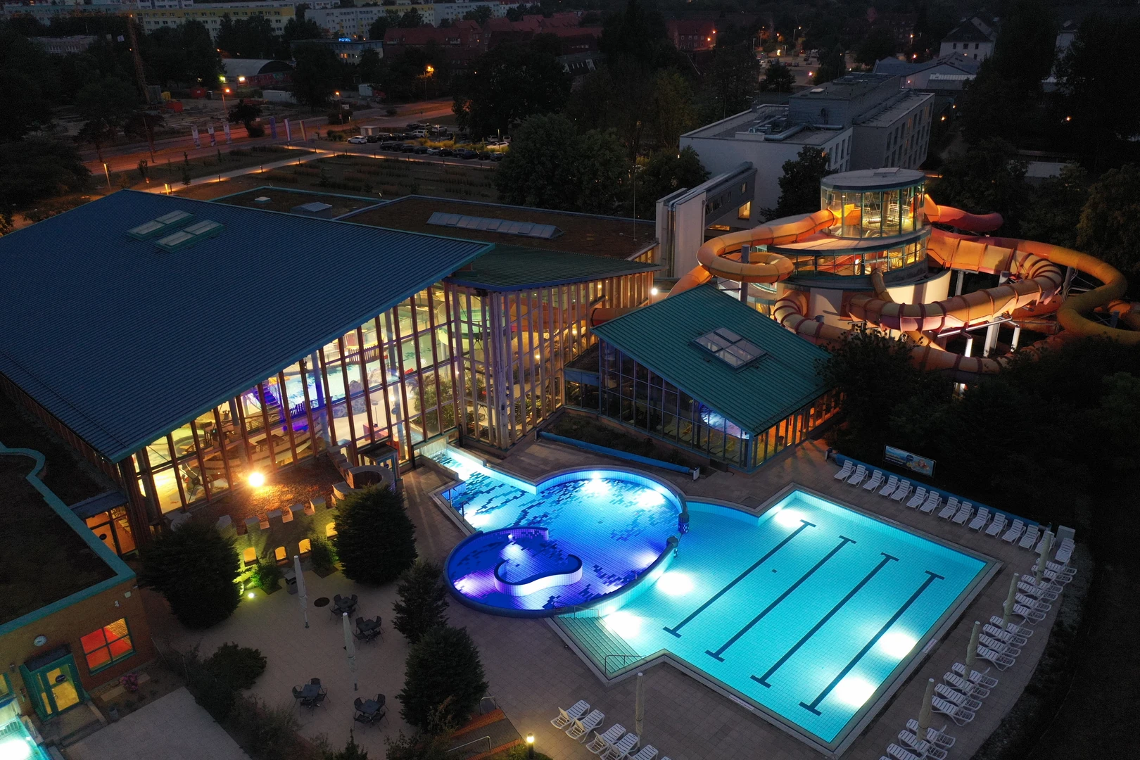 Das Wonnemar Resort in Wismar zeigt in einer Abendaufnahme seine beeindruckende Architektur mit beleuchteten Pools, einer vielseitigen Rutschenlandschaft und großen Glasfronten, die einladend und modern wirken.