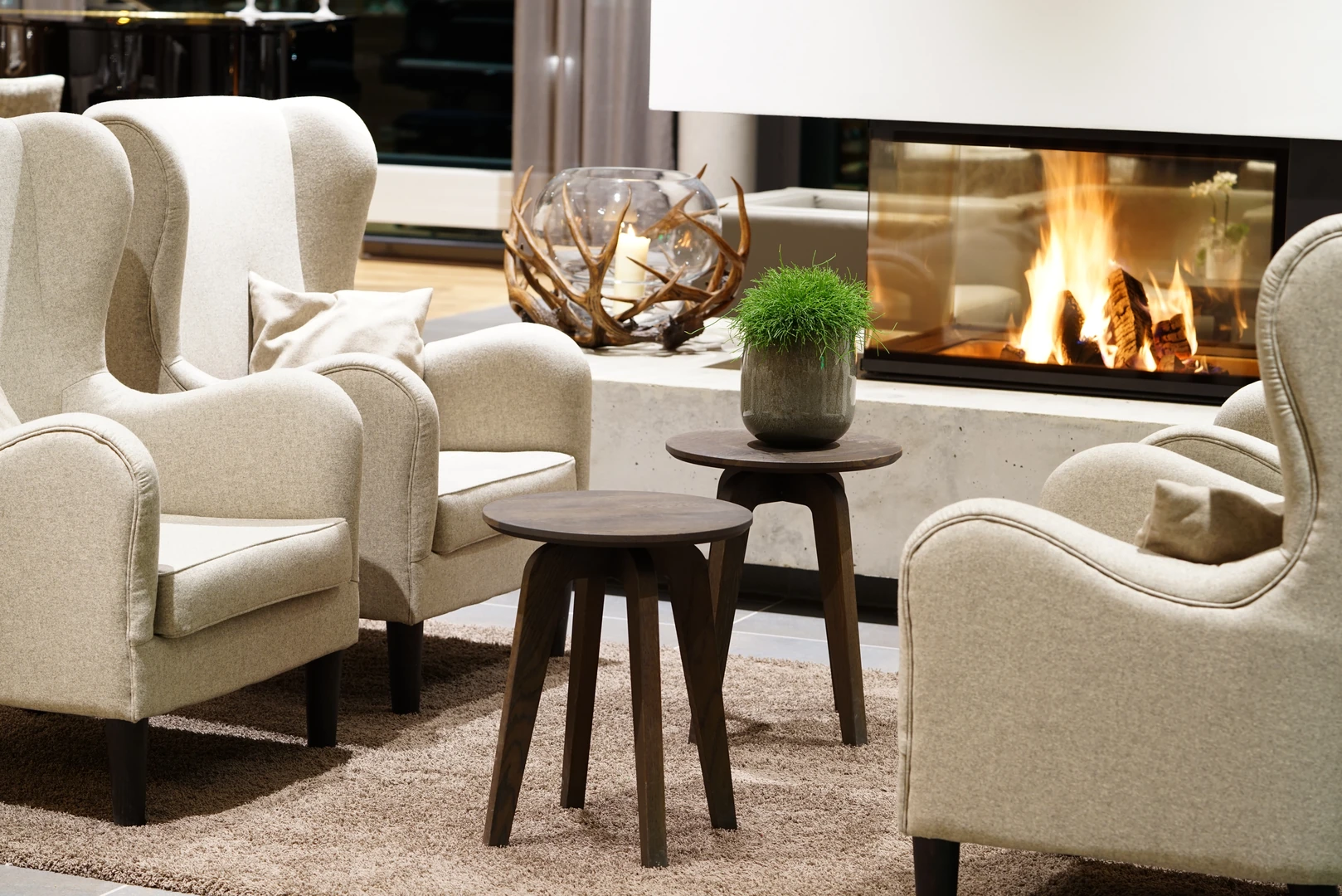 Gemütliche Lounge-Ecke im Wonnemar Resort Wismar mit bequemen Sesseln, stilvoller Dekoration und einem einladenden Kamin für entspannte Momente.