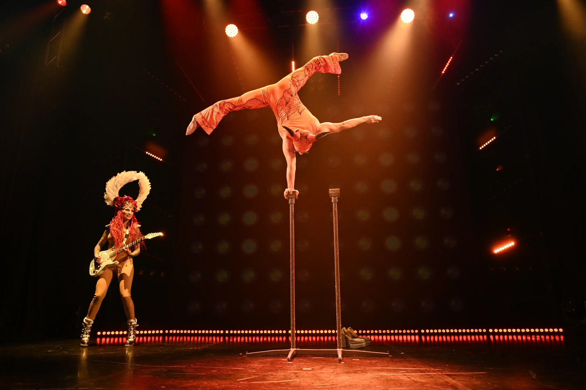 Akrobat mit E Gitarren Spielerin, verkleidet , auf einer Hand stehend