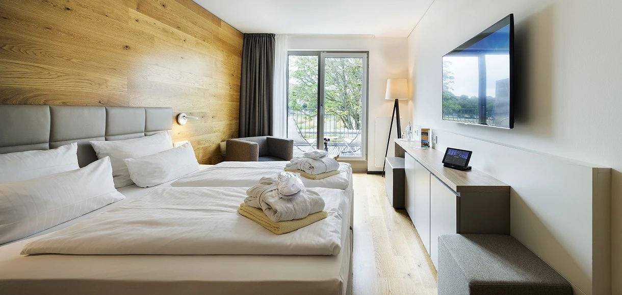 Modernes und helles Doppelzimmer im Wonnemar Resort Wismar mit stilvollem Holzdesign, gemütlicher Sitzecke und einem Balkon mit Ausblick für entspannte Momente.