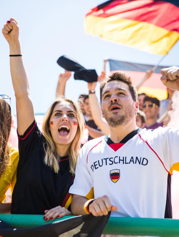 Junge Menschen jubeln mit erhobenen Fäusten und schwenken eine Deutschlandflagge