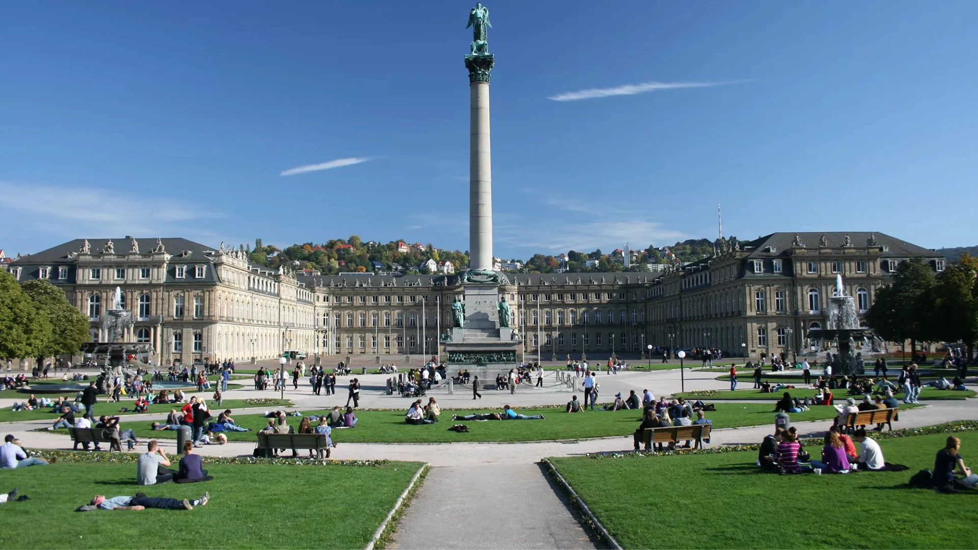Blick auf den Schlossplatz in Stuttgart mit Menschen und einem Denkmal.