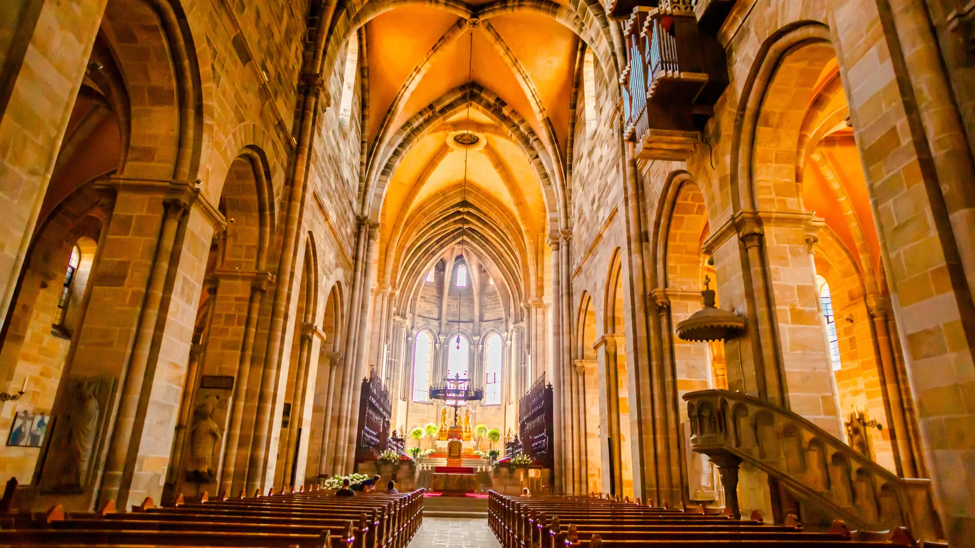 Das Bild zeigt den Innenraum des Bamberger Doms mit hohen Gewölben, Bänken und Altar im Hintergrund
