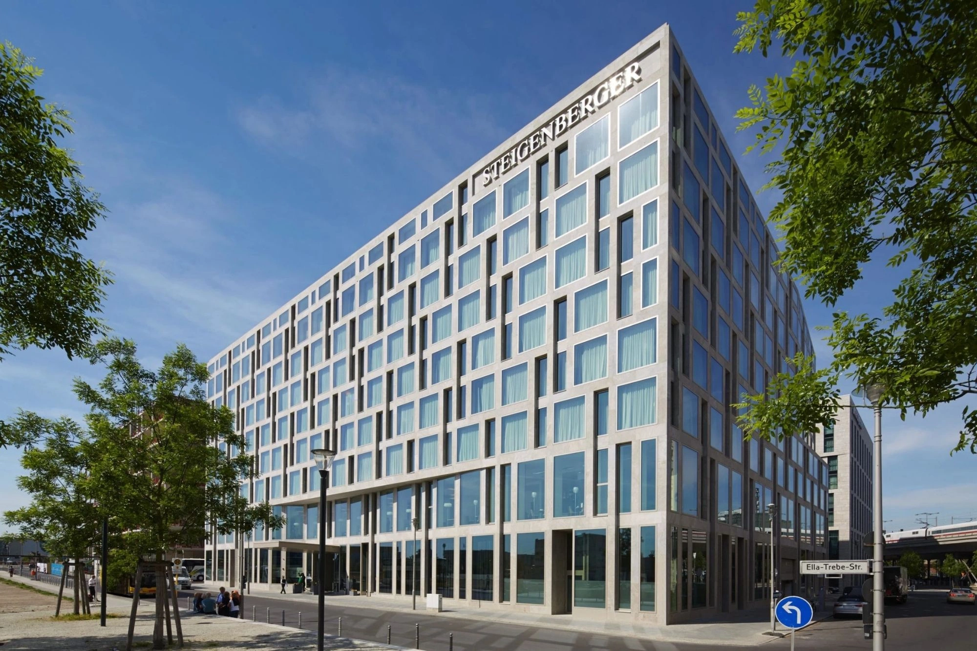 Die Außenansicht des Steigenberger Hotels am Kanzleramt in Berlin besticht durch eine moderne Fensterfassade, die das Gebäude in einem eleganten, geradlinigen Design präsentiert. Die klare Struktur der großflächigen Glasfenster reflektiert das Tageslicht und verleiht dem Hotel einen lichtdurchfluteten und offenen Charakter. Das Gebäude fügt sich harmonisch in die städtische Umgebung ein und strahlt eine zeitgenössische Eleganz aus, die das gehobene Ambiente des Hotels unterstreicht.