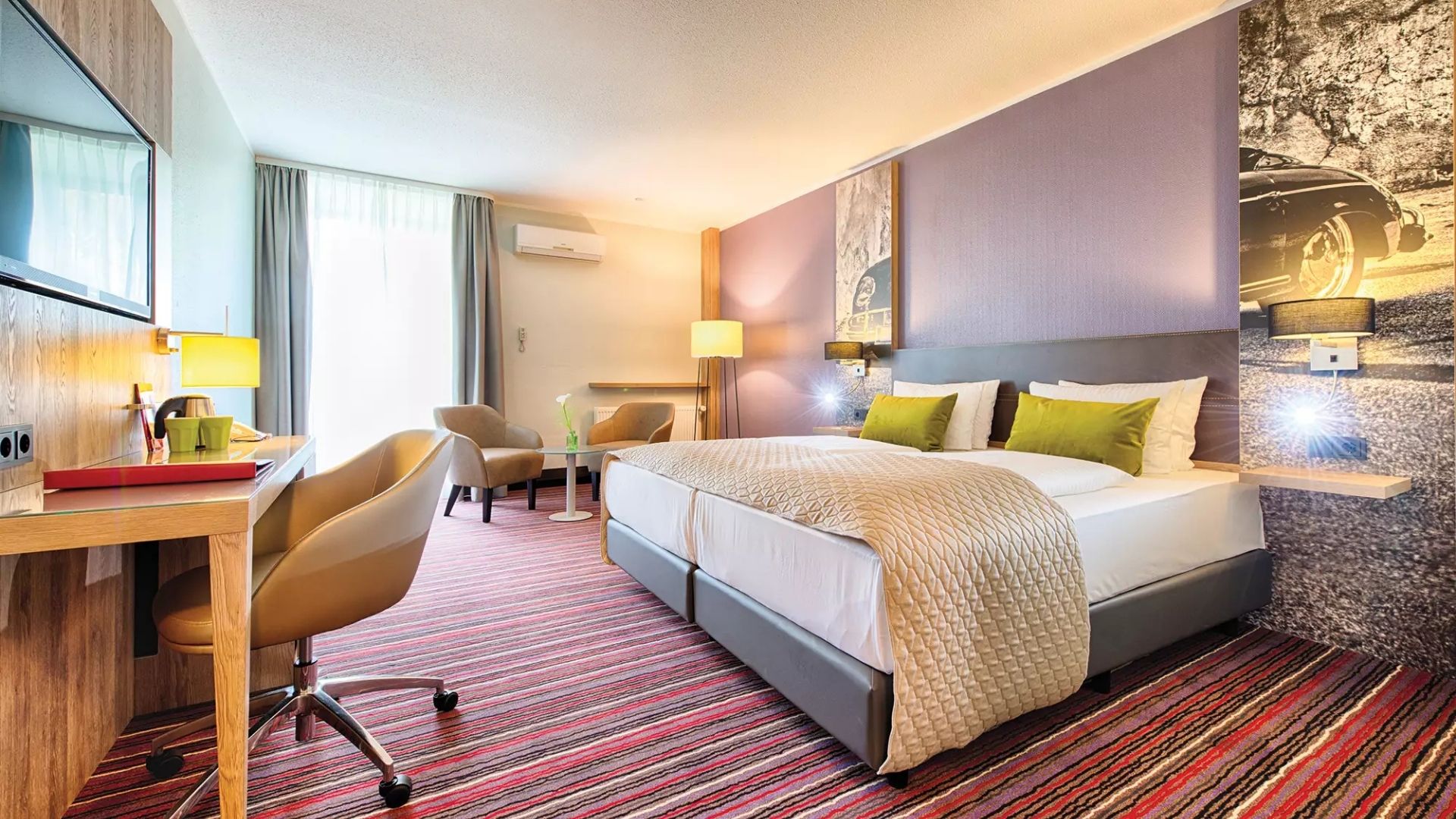 Helles geräumiges Zimmerbeispiel im Leonardo Hotel Wolfsburg mit Doppelbett, Schreibtisch und Fernseher