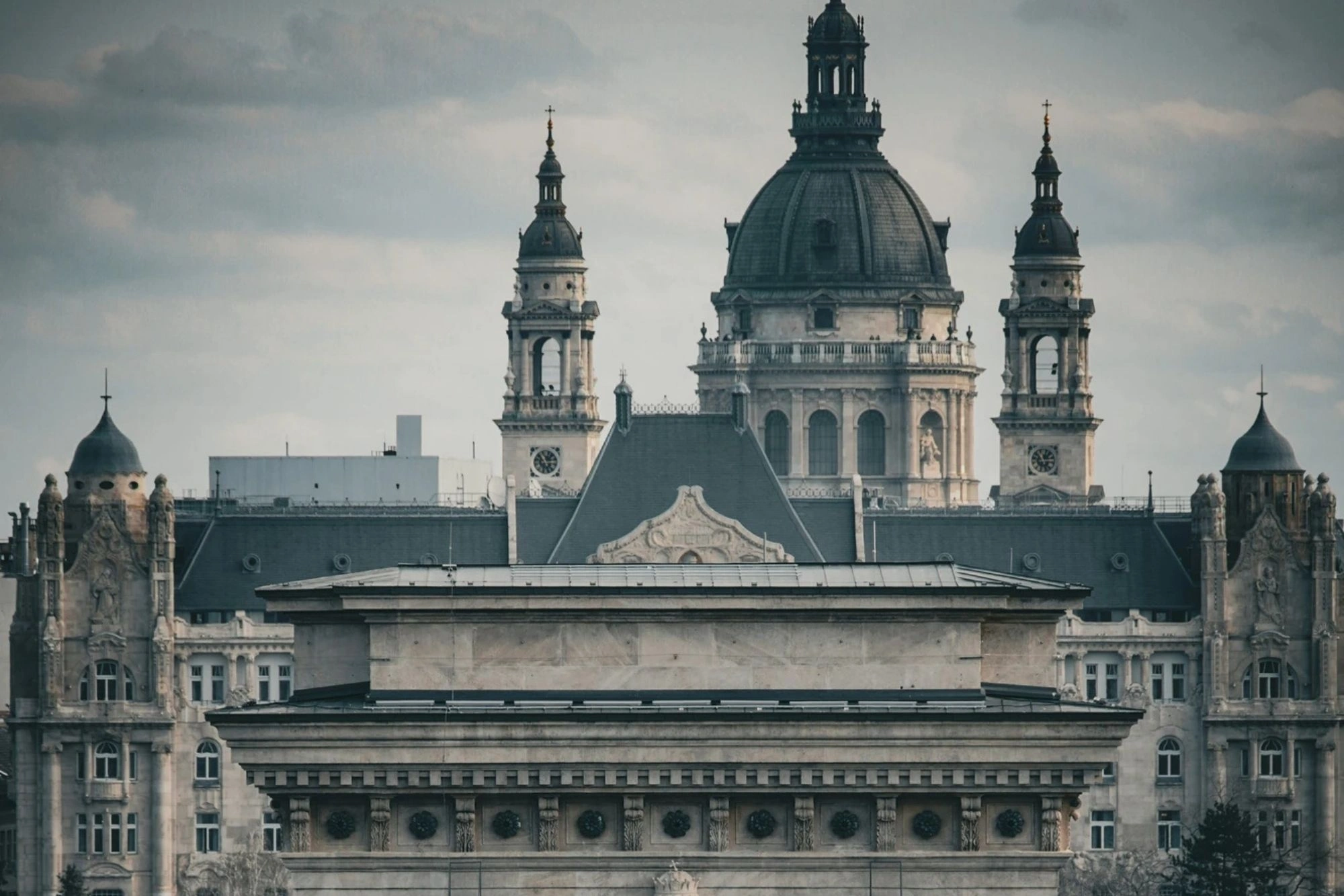 Städtereise Budapest zeigt die Kettenbrücke vor der St.-Stephans-Basilika unter bewölktem Himmel.