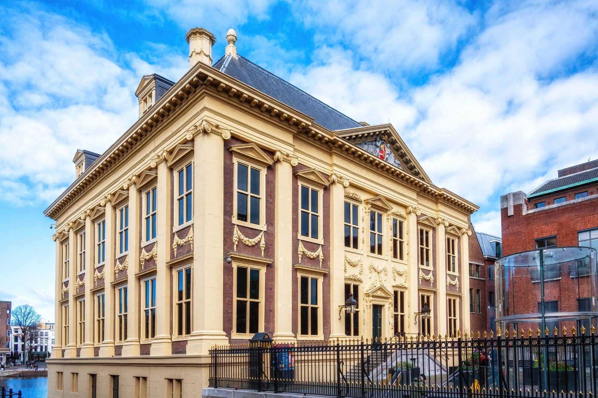 Gelbes historisches Gebäude mit vielen Fenstern und verziertem Giebel vor blauem Himmel