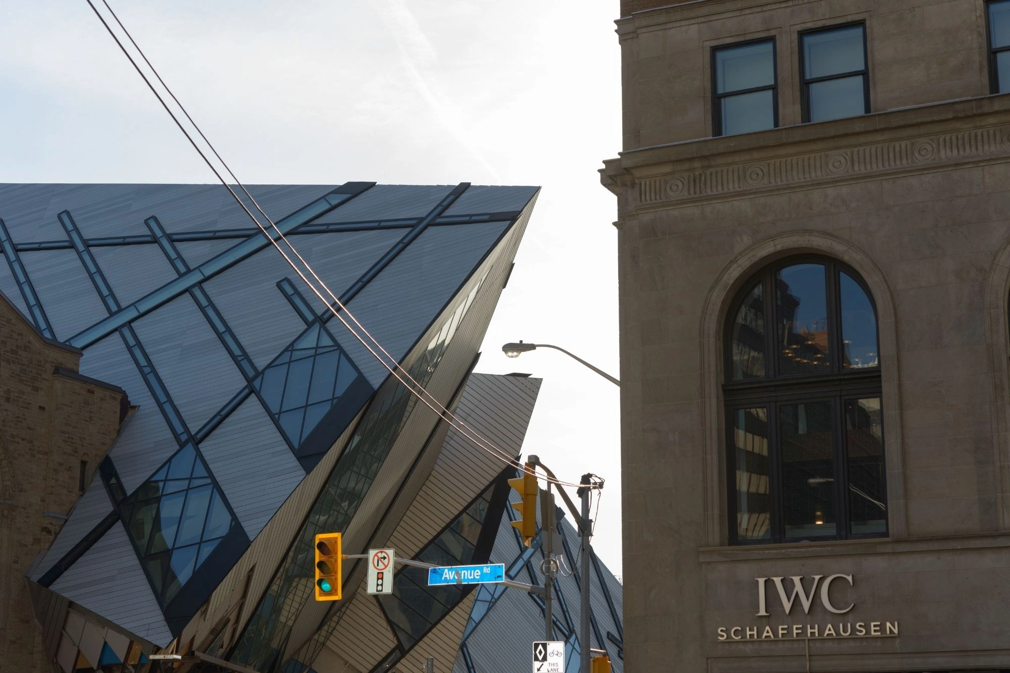 Moderne Glasfassade mit schrägen Linien neben einem historischen Gebäude mit großem Bogenfenster und Schriftzug 'IWC SCHAFFHAUSEN'