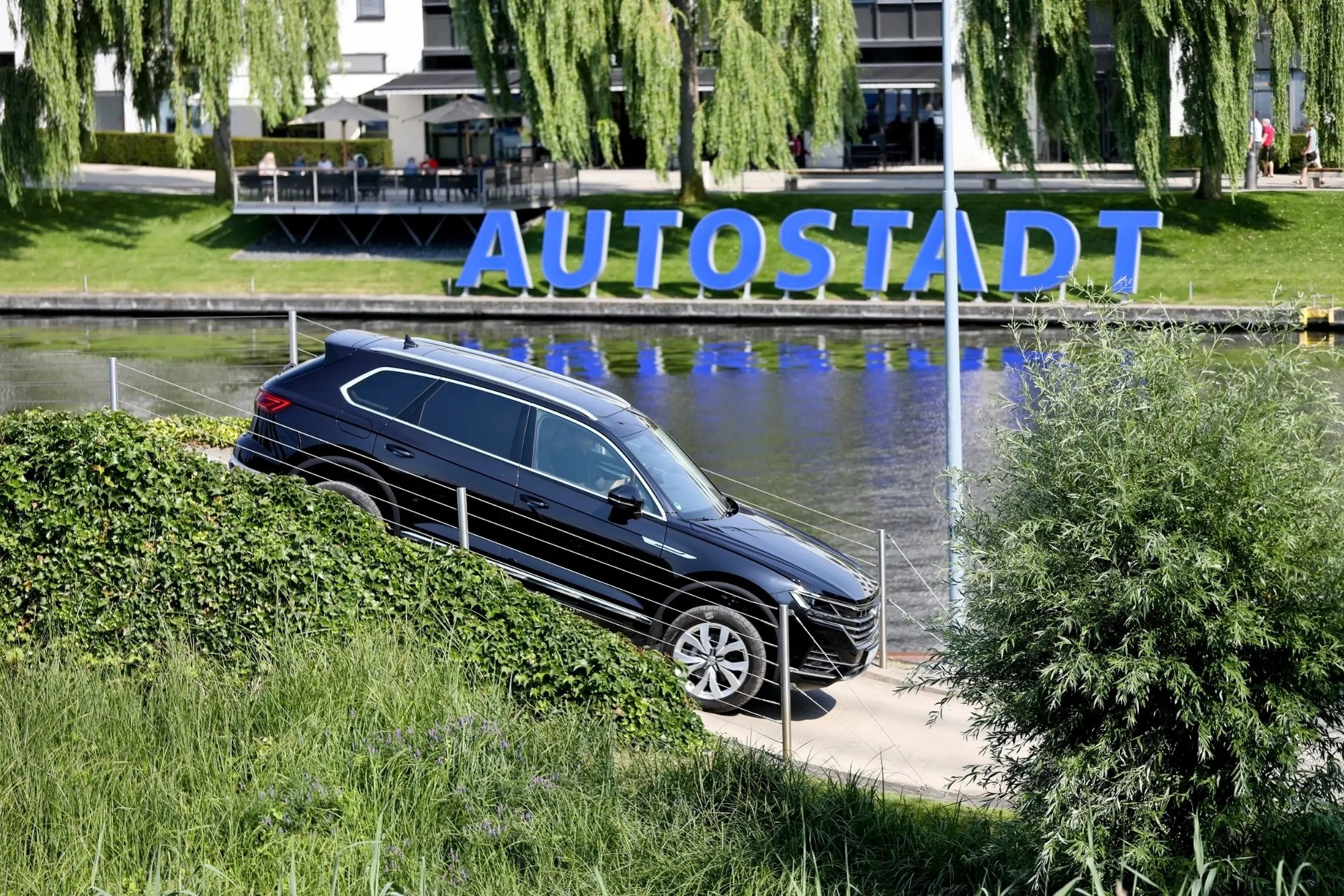 VW Autostadt Wolfsburg, Auto vor Schriftzug am Mittelland Kanal