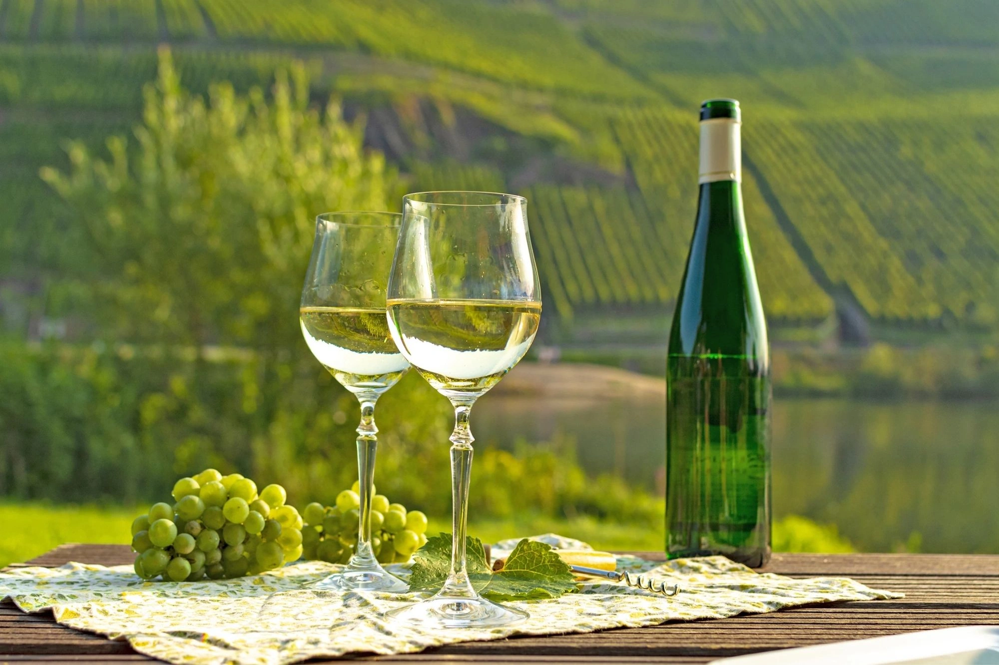 Riesling Weintrauben, Gläser und Weinflasche vor Weinbergen