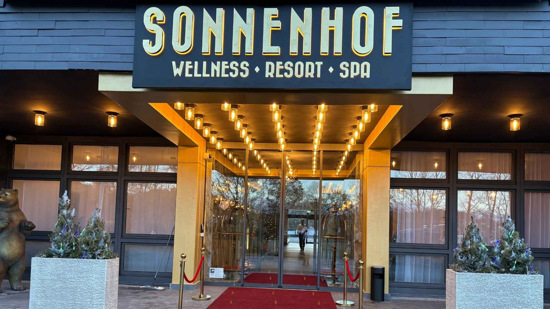 Eingangsbereich des Sonnenhof Wellness Resorts mit beleuchteter Fassade und rotem Teppich.